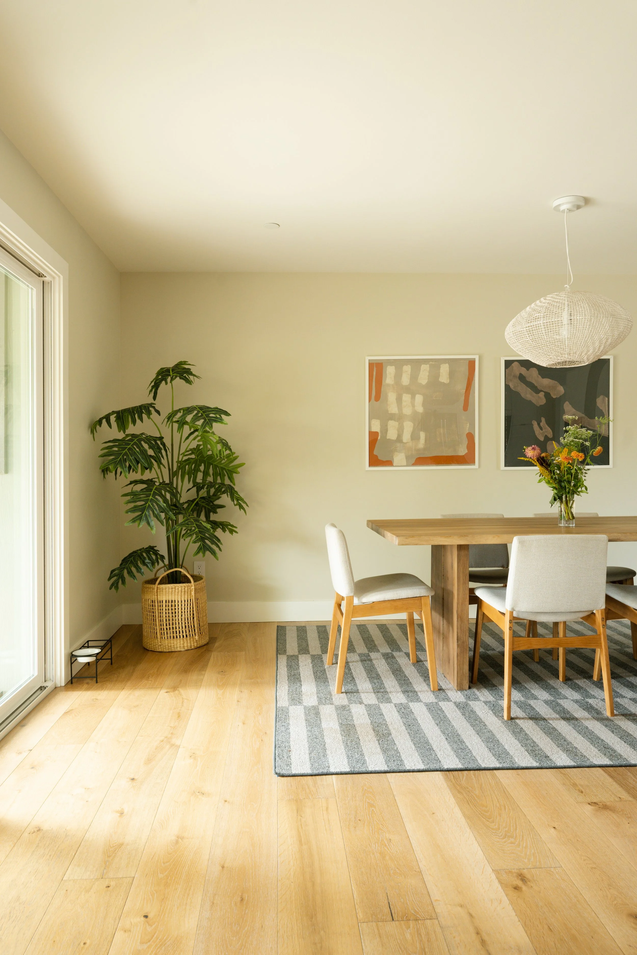 Residential dining room with oak floors, striped rug and plants
