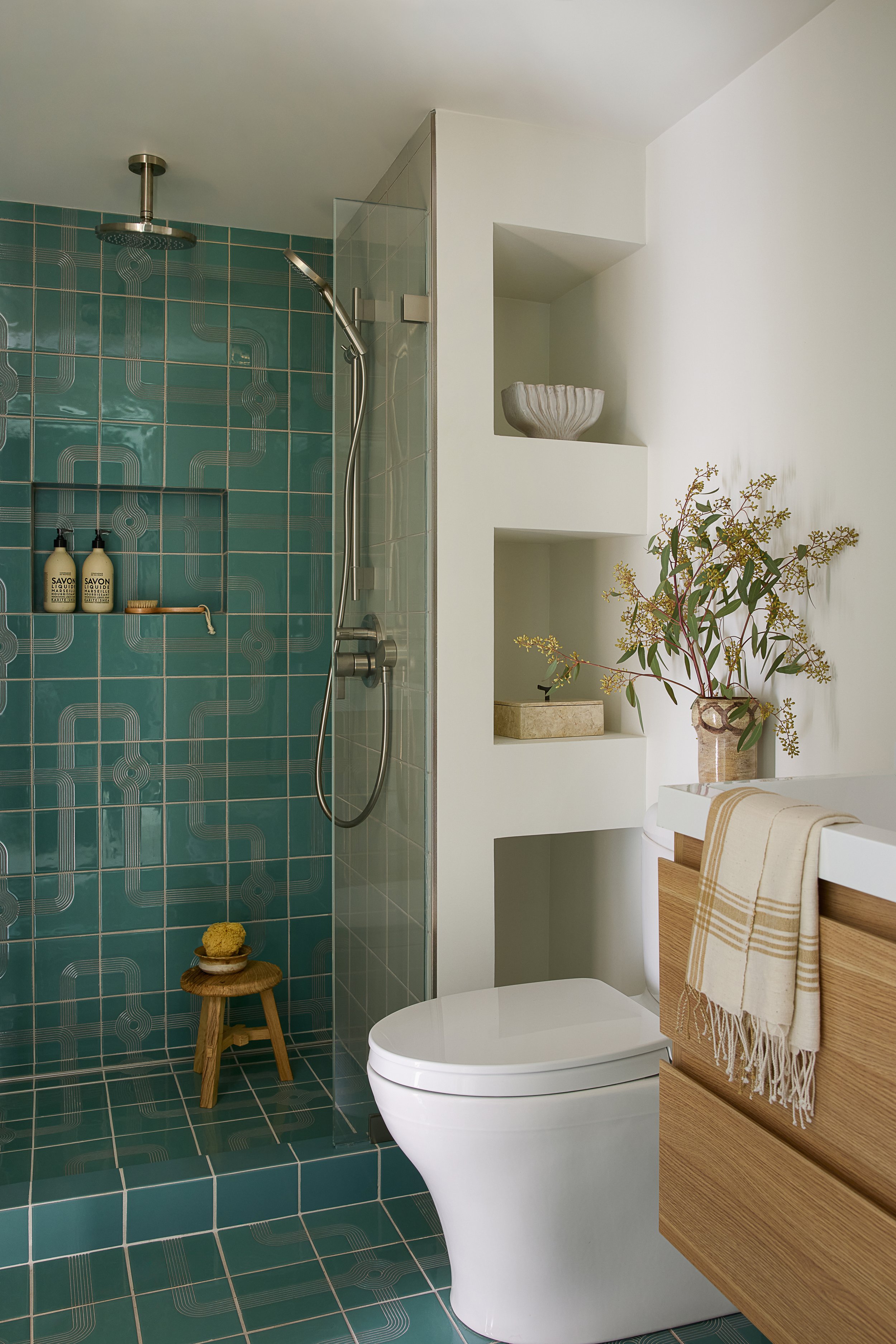 Residential bathroom with shower and shelves featuring hand painted green tile