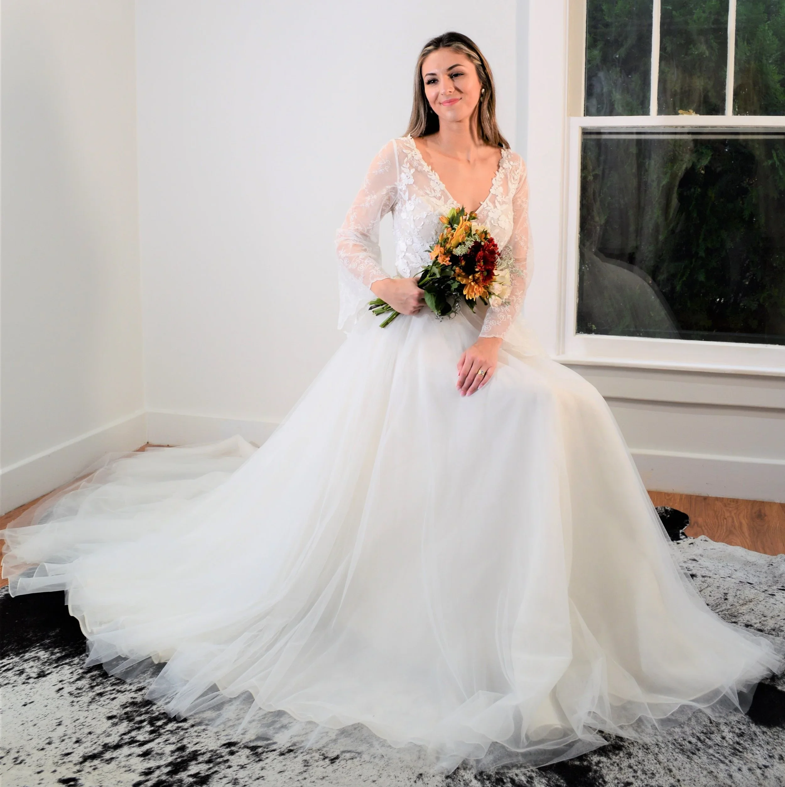 A bride wearing a dress by Maria from Romantic Creations Bridal. The bride is holding a bouquet of flowers