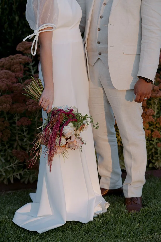 Shepparton Wedding Photography. A bride and groom standing outdoors at Olivehouse at Greendale Grove, with the bride holding a bouquet of flowers, both dressed in wedding attire.