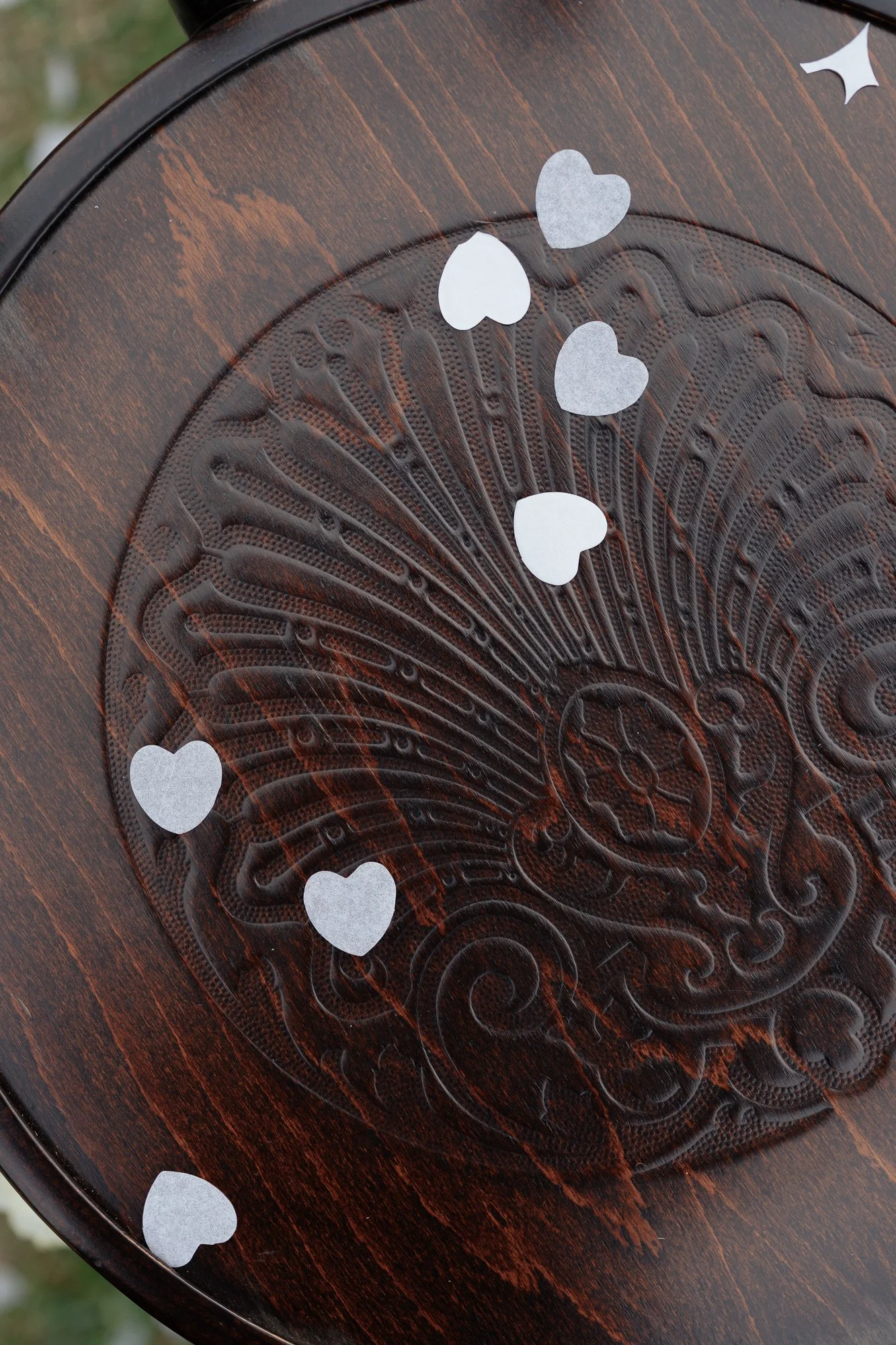 Decorative wooden surface with an intricate carved design, adorned with small white paper hearts.