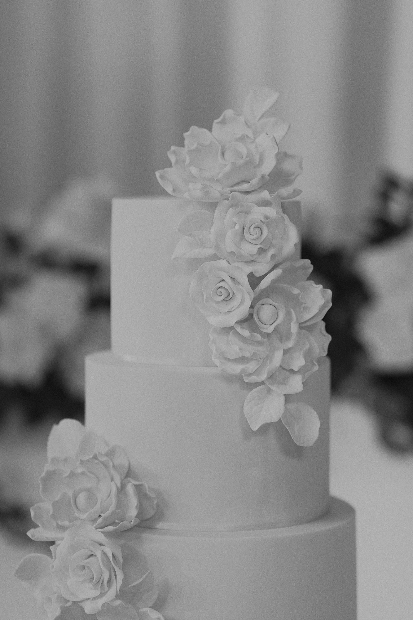 A three-tiered wedding cake decorated with cascading sugar roses on top and along the side. Whitestone Bentleigh East.