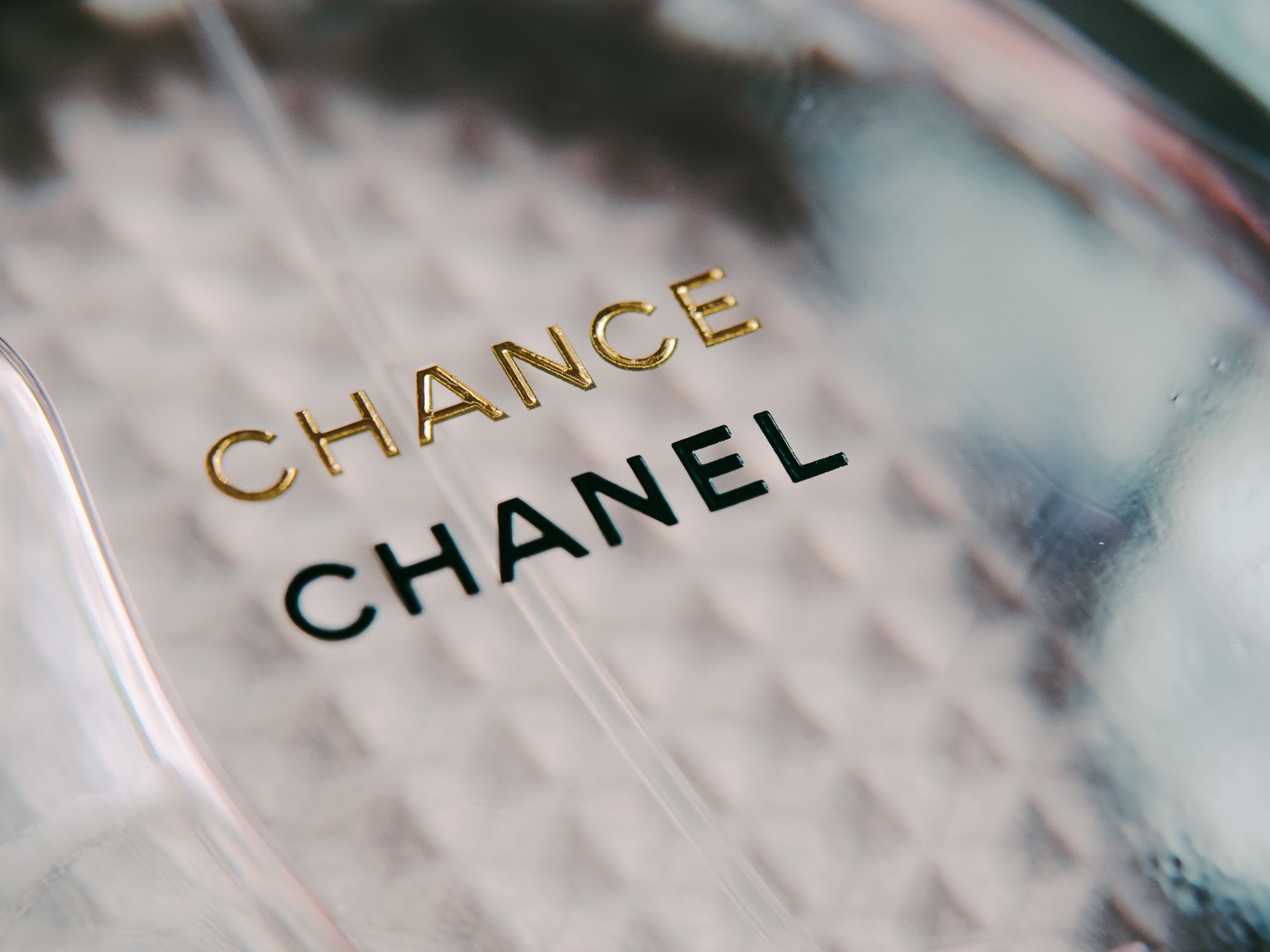 Close-up of a Chanel Chance perfume bottle with the brand name 'CHANEL' in black and gold lettering.