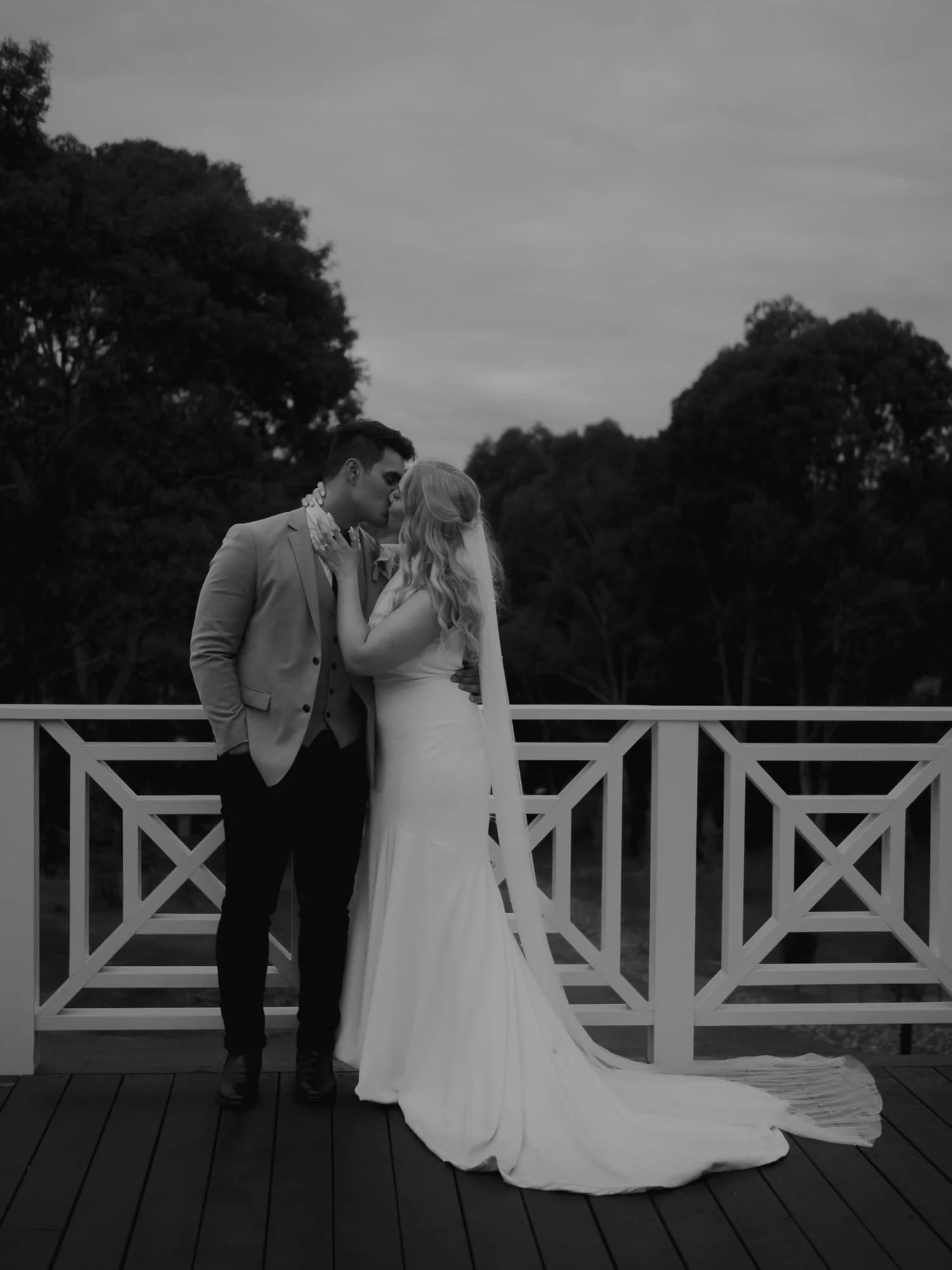 Melbourne Wedding Photography. A black and white photo of a bride and groom sharing a kiss at Bramleigh Estate with trees in the background.