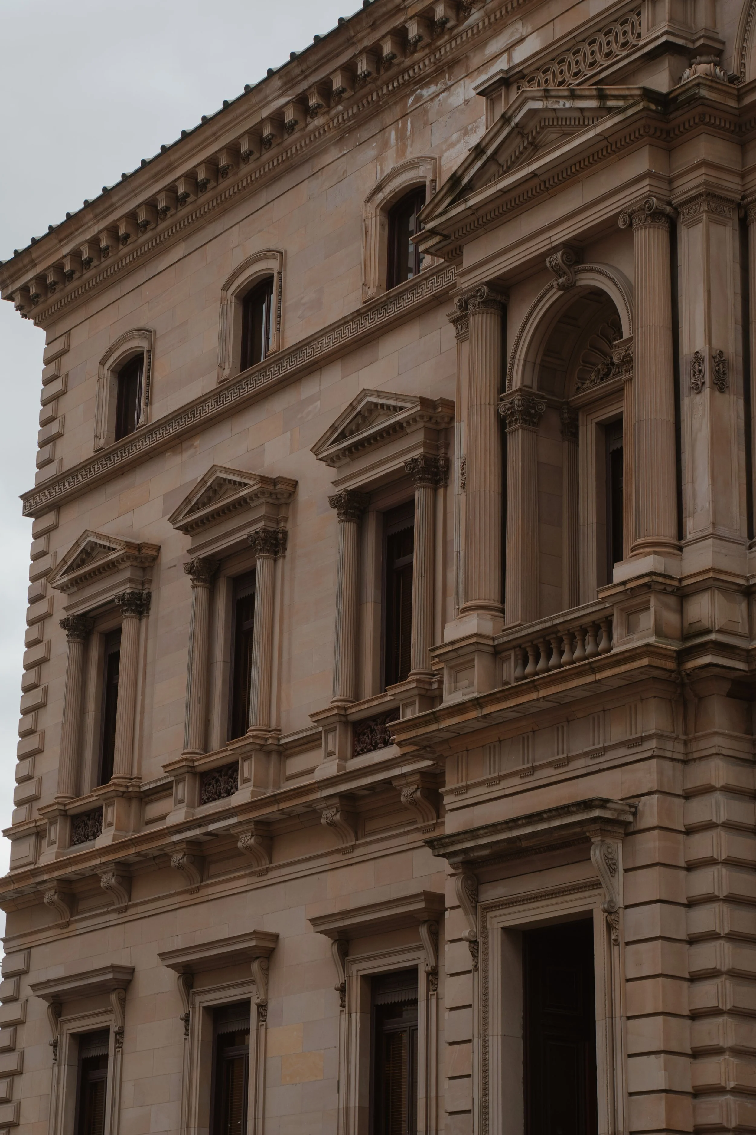Close-up of a historic beige stone building with ornate architectural details, including columns, pilasters, decorative window frames, and cornices. The Treasury Building, perfect for Melbourne Elopement Photography.
