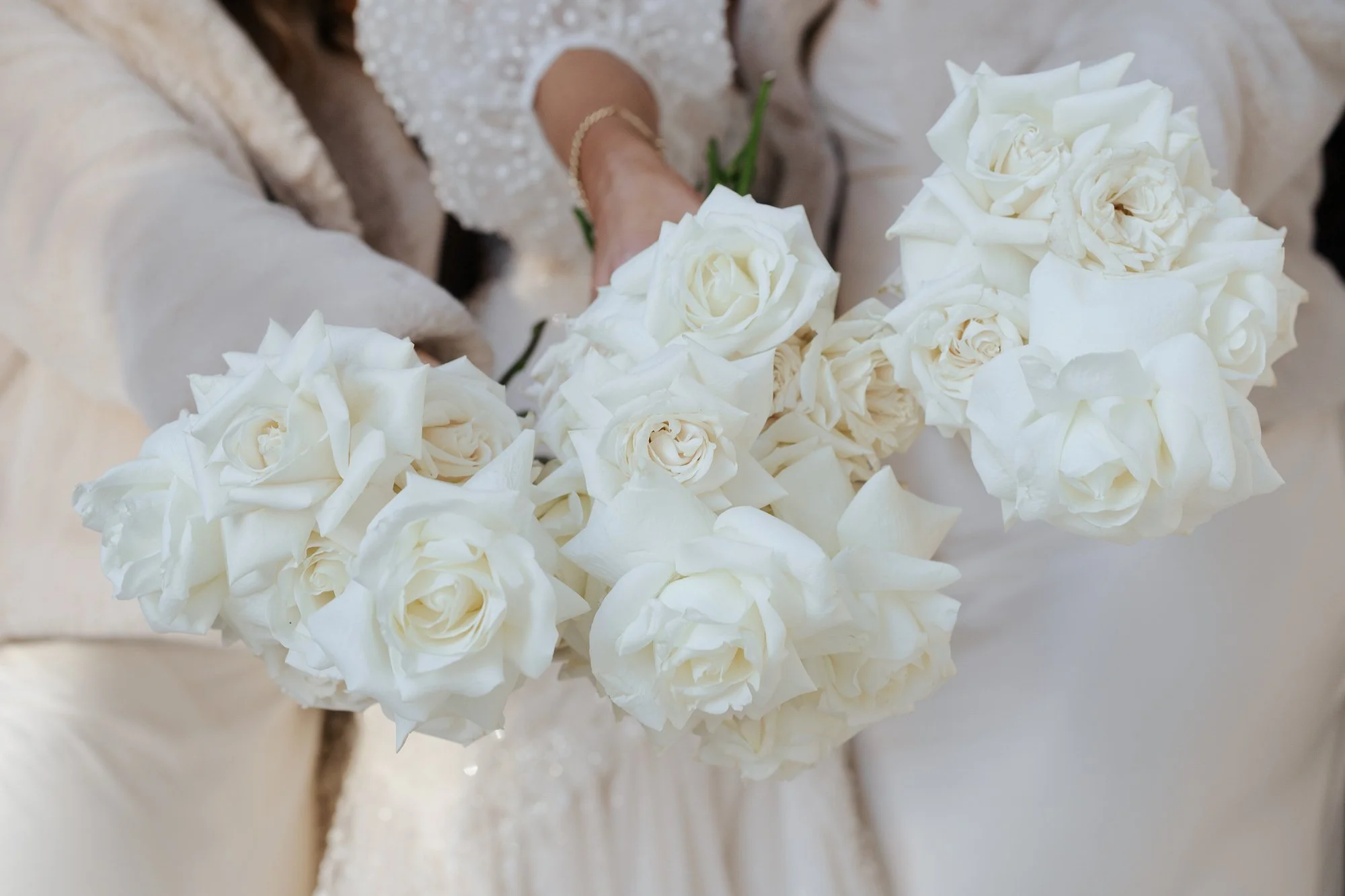 People holding bouquets of white roses.