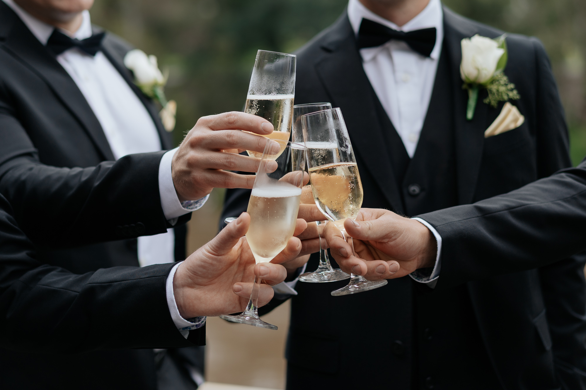 Group of people in tuxedos celebrating with glasses of champagne. Leonda by the Yarra