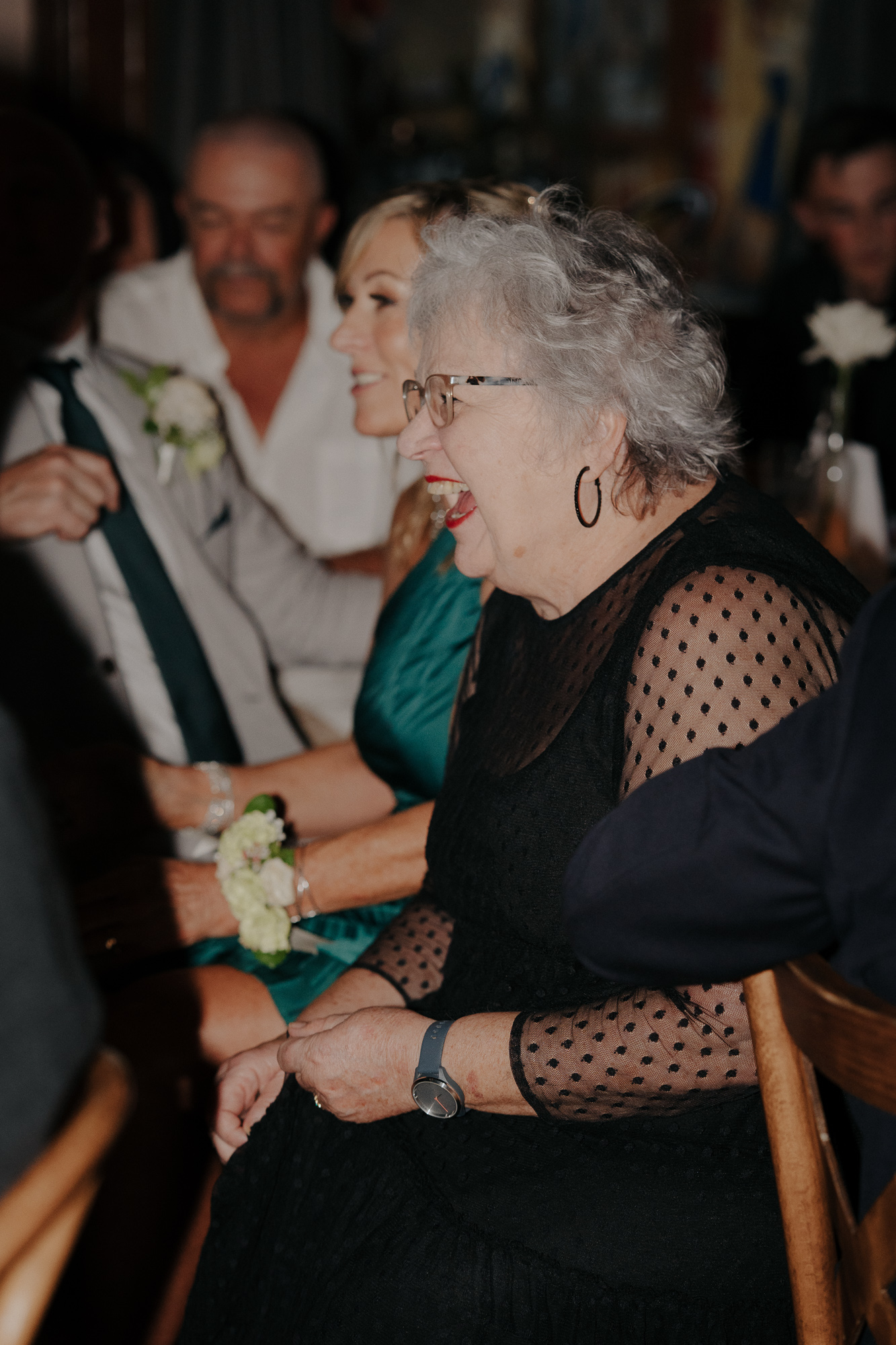 A group of people sitting together, smiling and laughing at a social gathering or celebration.