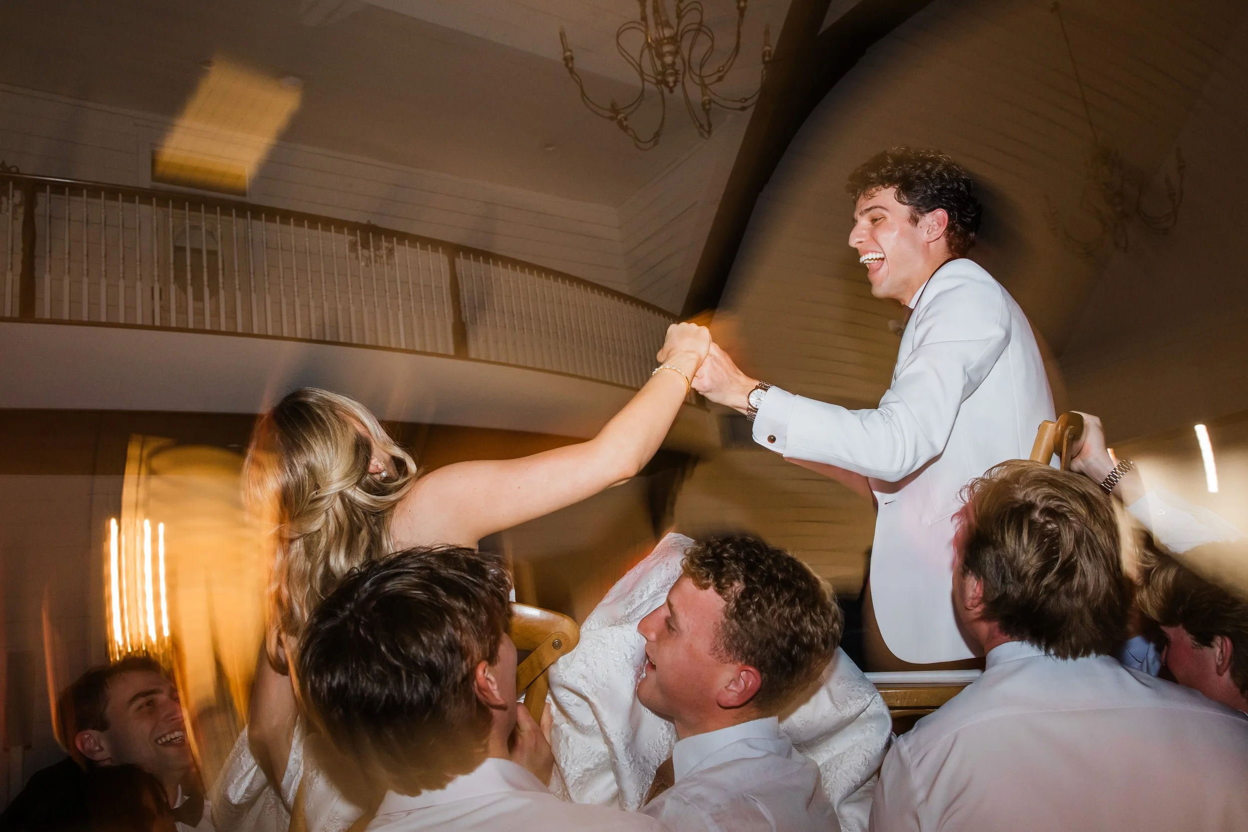 Bride and groom on chairs in the air during wedding reception at the French Farmhouse Venue at Collinsville TX