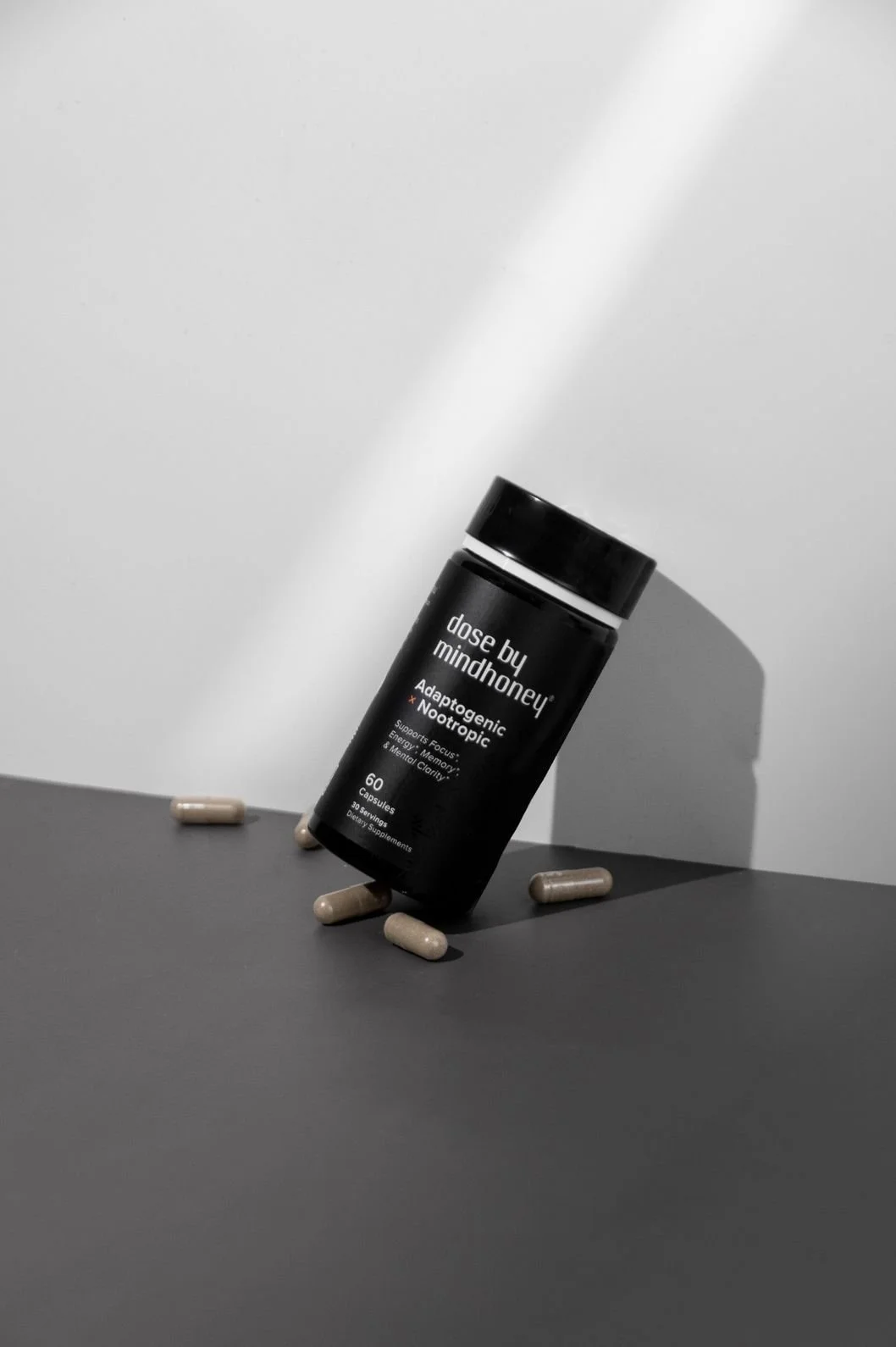 Supplements product photography of a bottle leaning against the wall with a few scattered pills on the tabletop