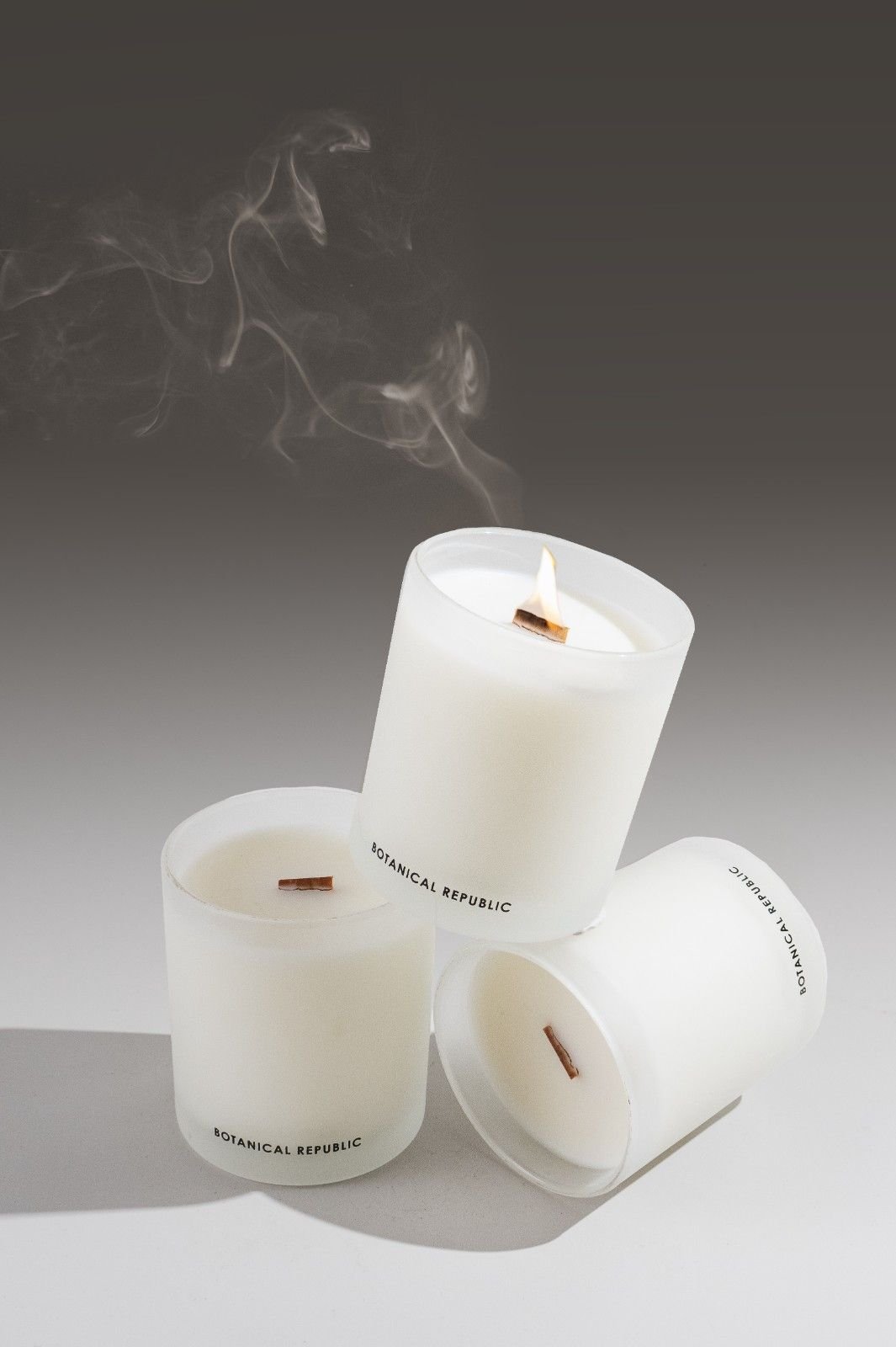 Seattle candle product photography of three white candles stacked on top of each other with smoke and a gradient grey background