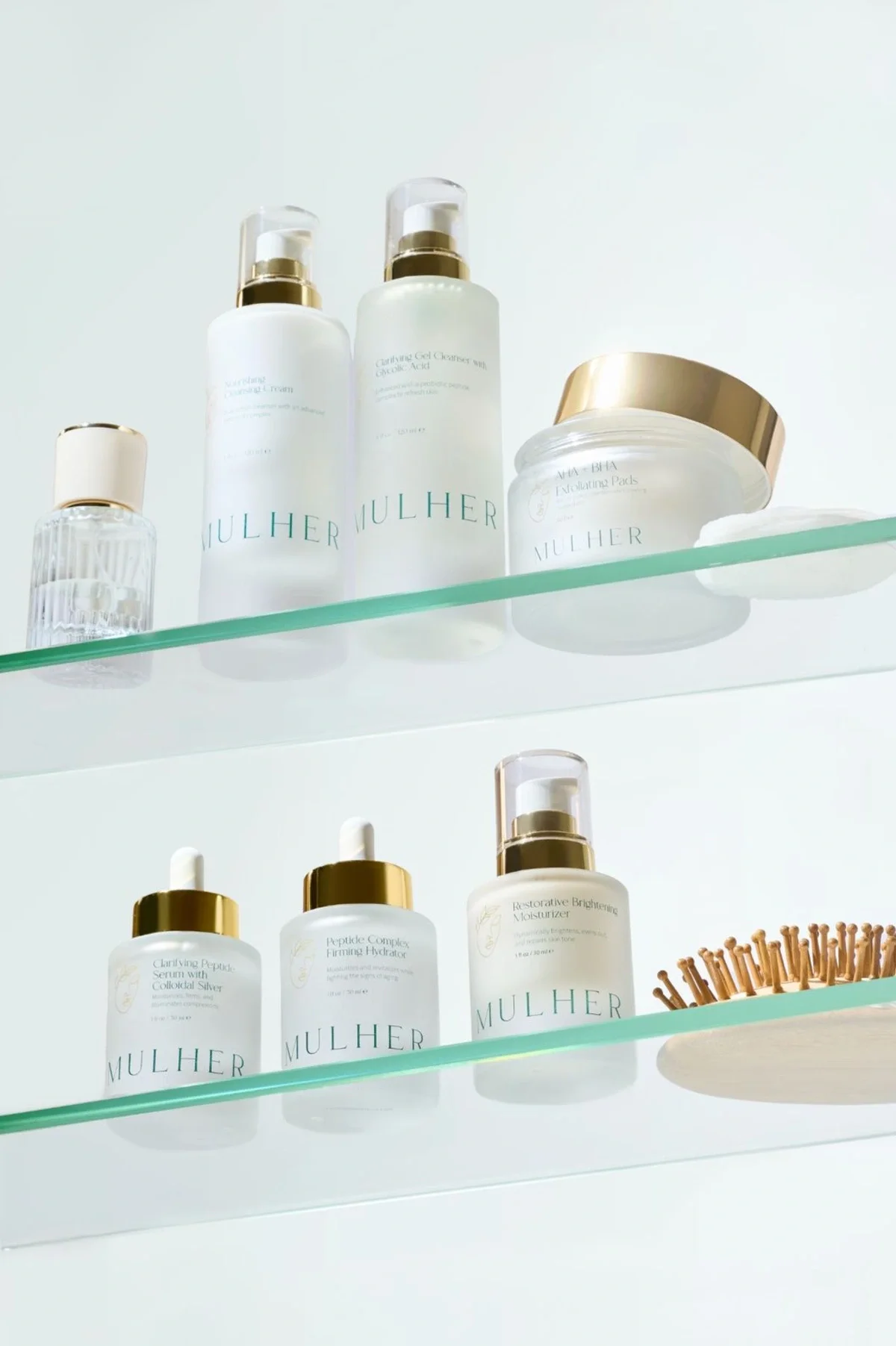 Skincare product photography of products on two glass shelves with hairbrush and perfume bottle. Photo for e-commerce, campaign, and marketing.