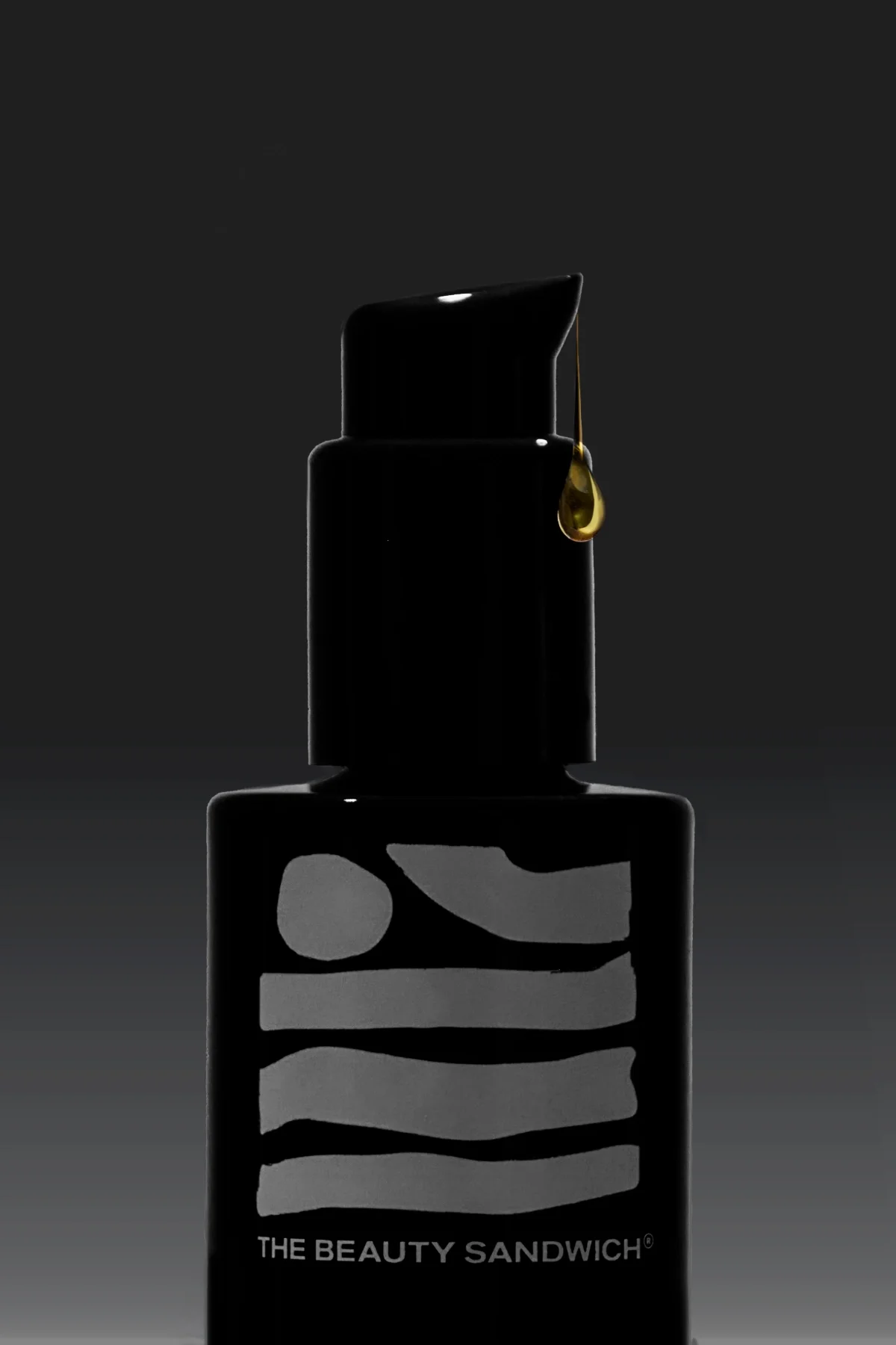 Luxury skincare product photography of a black serum bottle with a pump dispenser, featuring a golden drop of serum oil suspended from the nozzle, set against a dark gradient background with dramatic, moody lighting—ideal for premium beauty brands, e