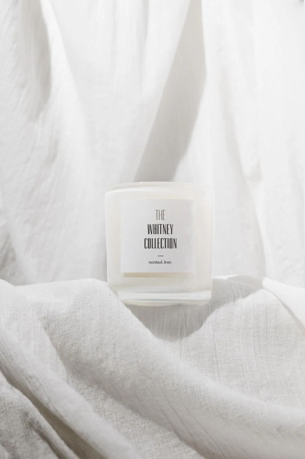 Seattle candle product photography of a white candle surrounded by draped white linen fabric
