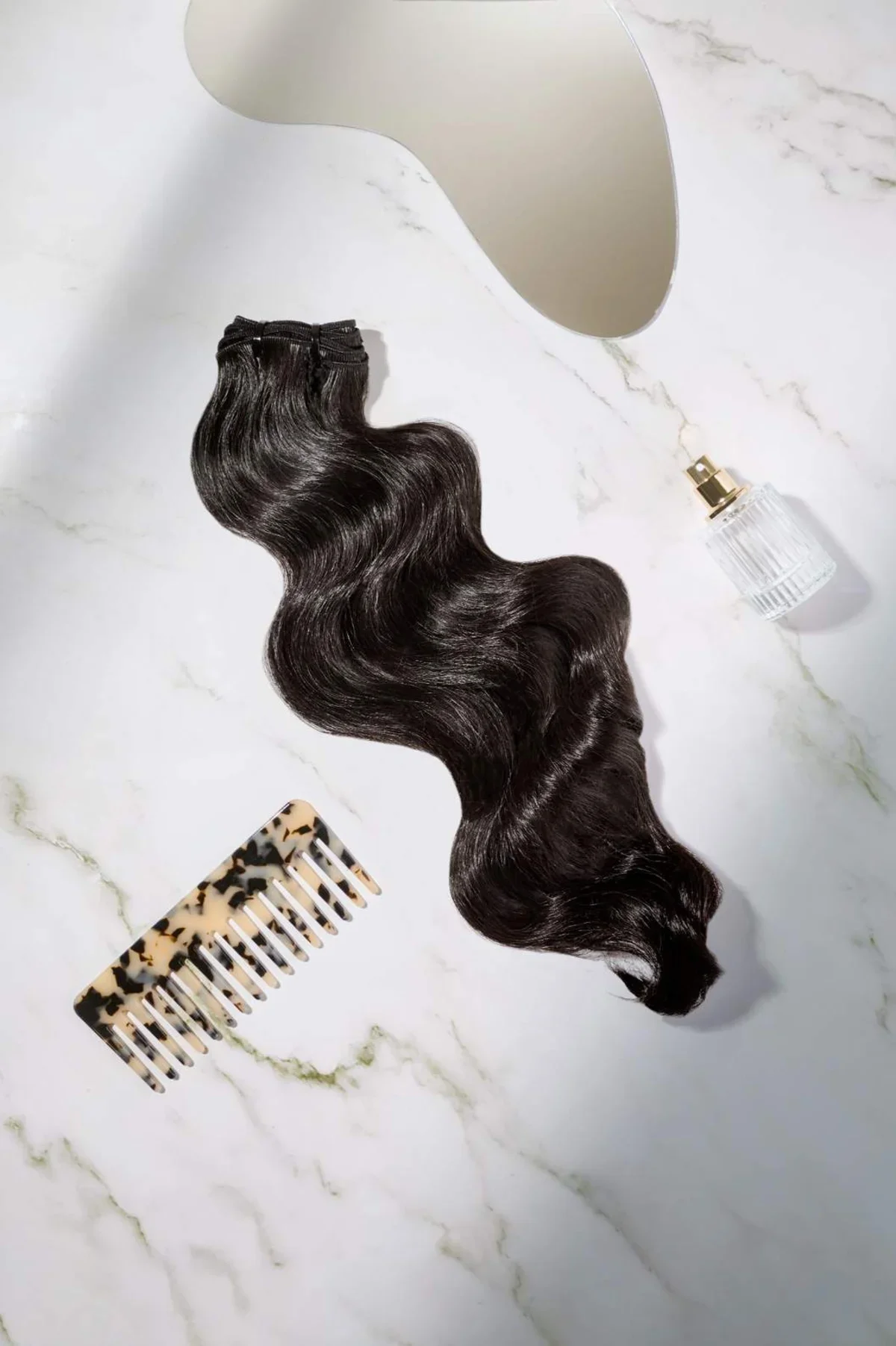 Hair extension product photography on marble with mirror, hair comb, and perfume bottle. Photo for e-commerce, campaigns, and marketing.