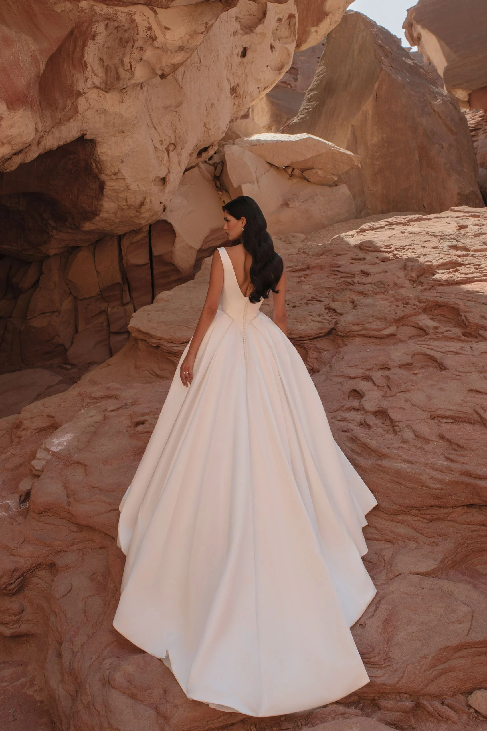 Discover Tori, a minimalist satin princess wedding dress with bateau neckline, structured corset, pearl waist detail and hidden pockets. Available at Spellbound Bridal Ireland.