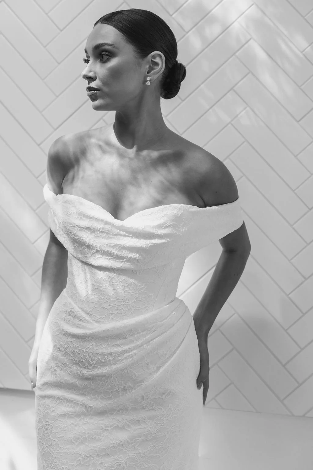 Rosalie by Trish Peng fitted Chantilly lace wedding dress featuring a soft sweetheart off-the-shoulder neckline, draped bodice, ruched skirt and sculpted hourglass silhouette, available at Spellbound Bridal Ireland.
