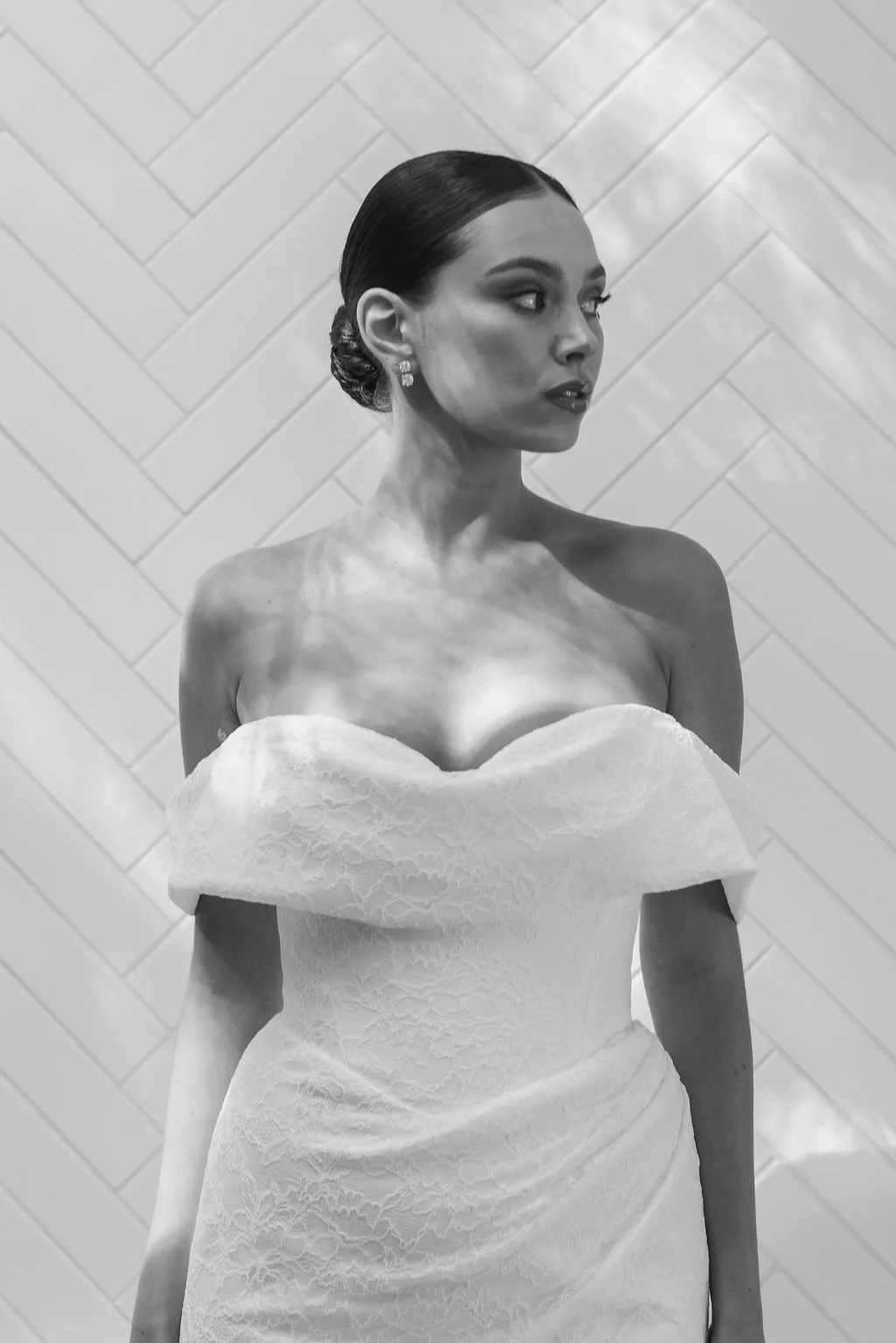 Rosalie by Trish Peng fitted Chantilly lace wedding dress featuring a soft sweetheart off-the-shoulder neckline, draped bodice, ruched skirt and sculpted hourglass silhouette, available at Spellbound Bridal Ireland.
