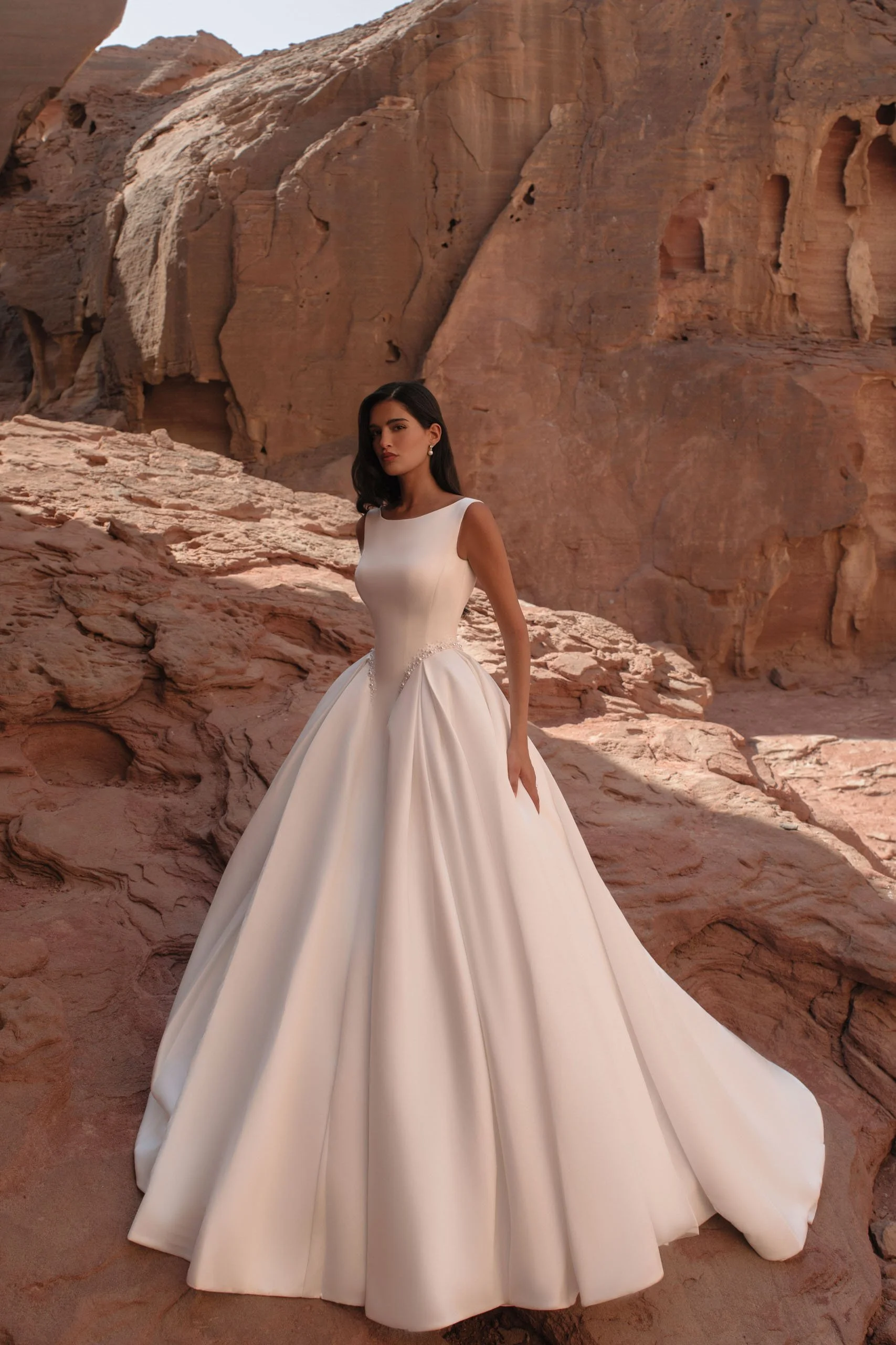 Discover Tori, a minimalist satin princess wedding dress with bateau neckline, structured corset, pearl waist detail and hidden pockets. Available at Spellbound Bridal Ireland.