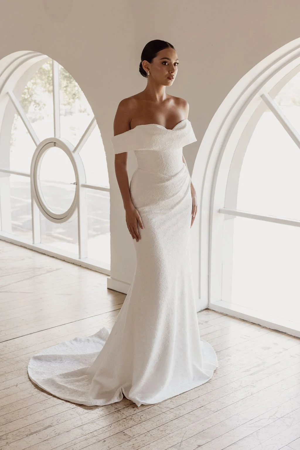 Rosalie by Trish Peng fitted Chantilly lace wedding dress featuring a soft sweetheart off-the-shoulder neckline, draped bodice, ruched skirt and sculpted hourglass silhouette, available at Spellbound Bridal Ireland.