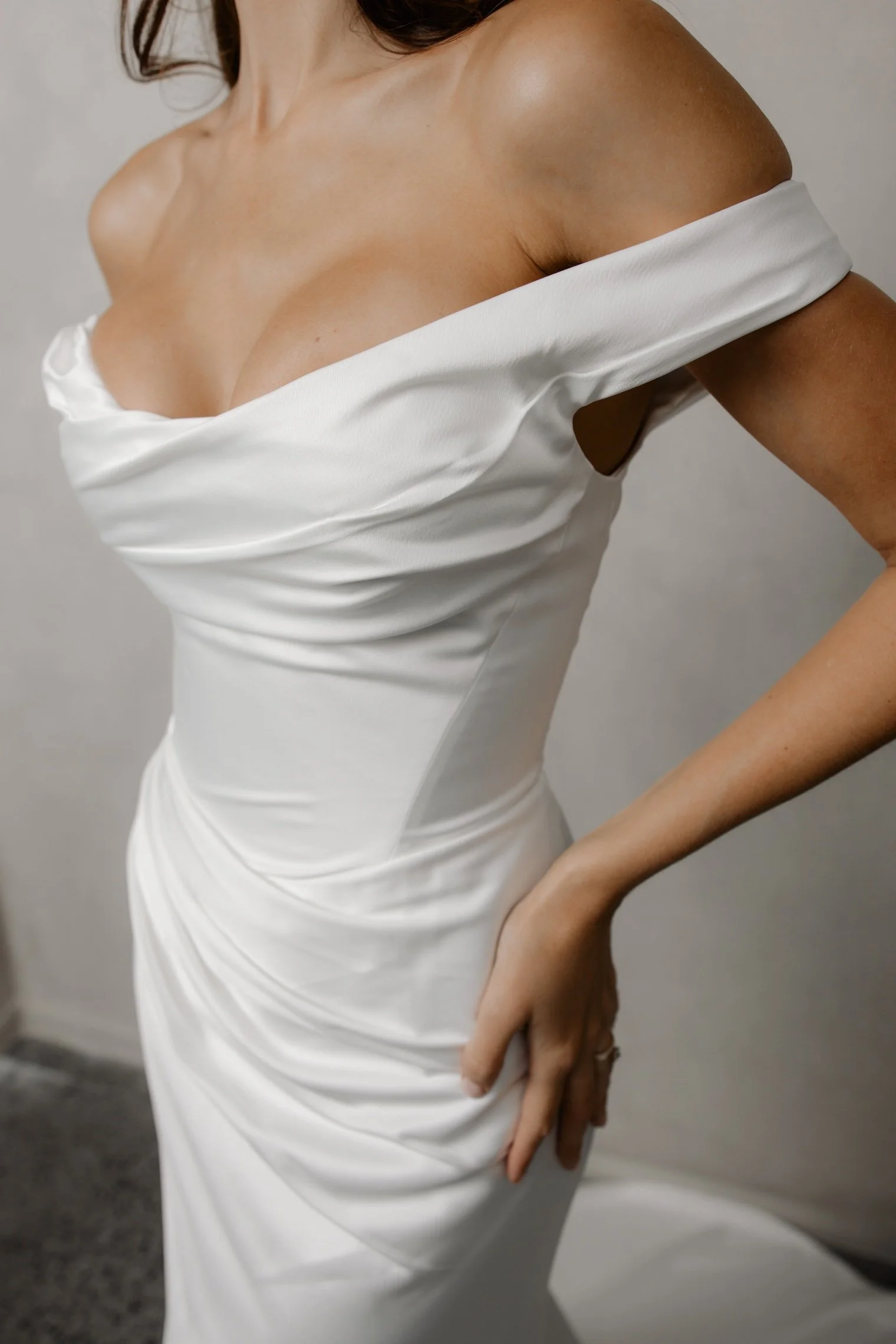 Lydia by Trish Peng satin wedding dress featuring a soft off-the-shoulder neckline, draped bodice, sculpted basque waist and fitted ruched skirt, available at Spellbound Bridal Ireland.