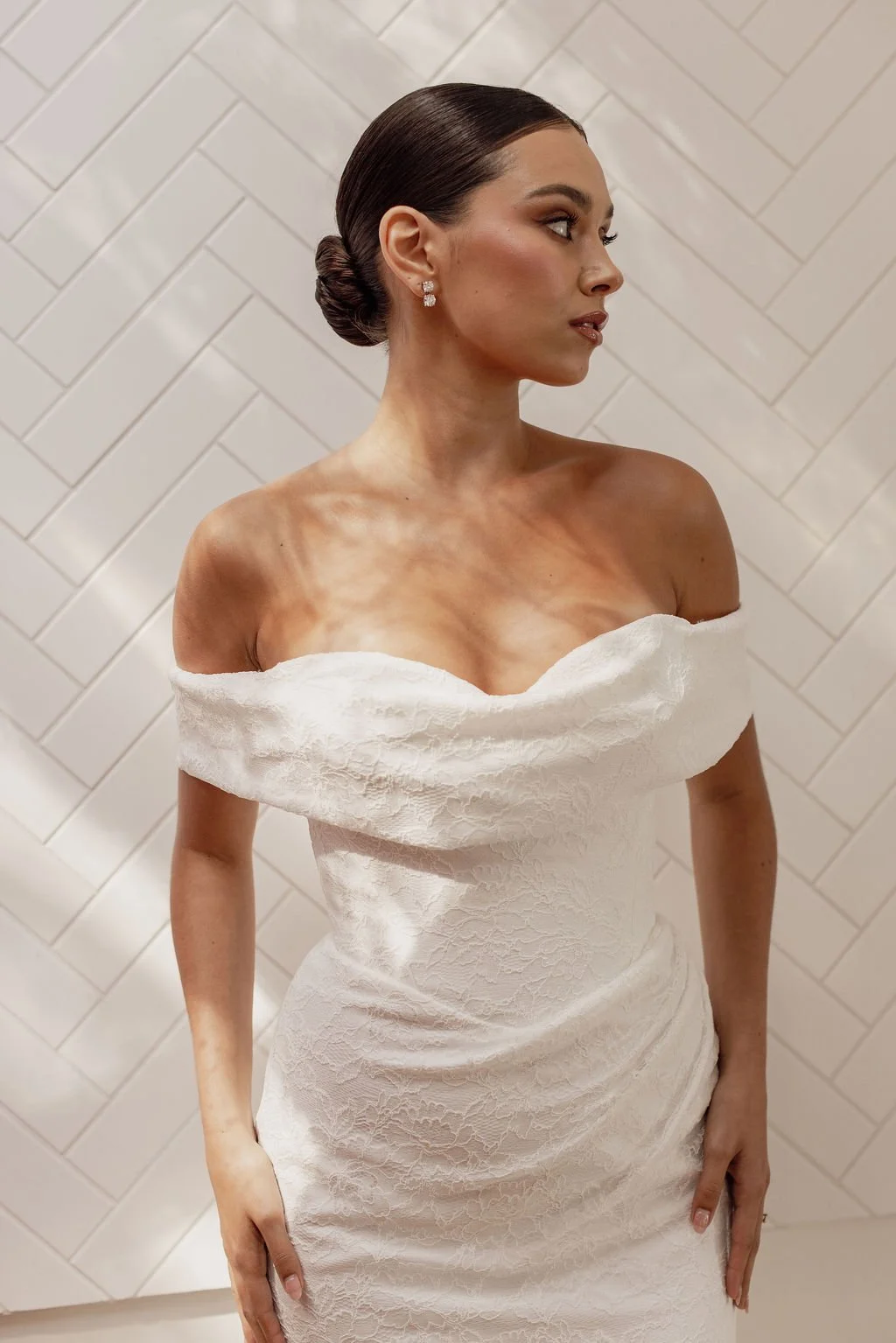 Rosalie by Trish Peng fitted Chantilly lace wedding dress featuring a soft sweetheart off-the-shoulder neckline, draped bodice, ruched skirt and sculpted hourglass silhouette, available at Spellbound Bridal Ireland.
