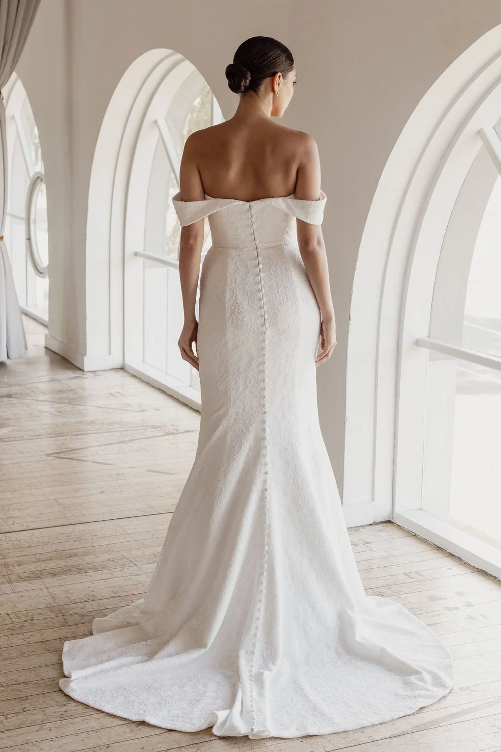 Rosalie by Trish Peng fitted Chantilly lace wedding dress featuring a soft sweetheart off-the-shoulder neckline, draped bodice, ruched skirt and sculpted hourglass silhouette, available at Spellbound Bridal Ireland.
