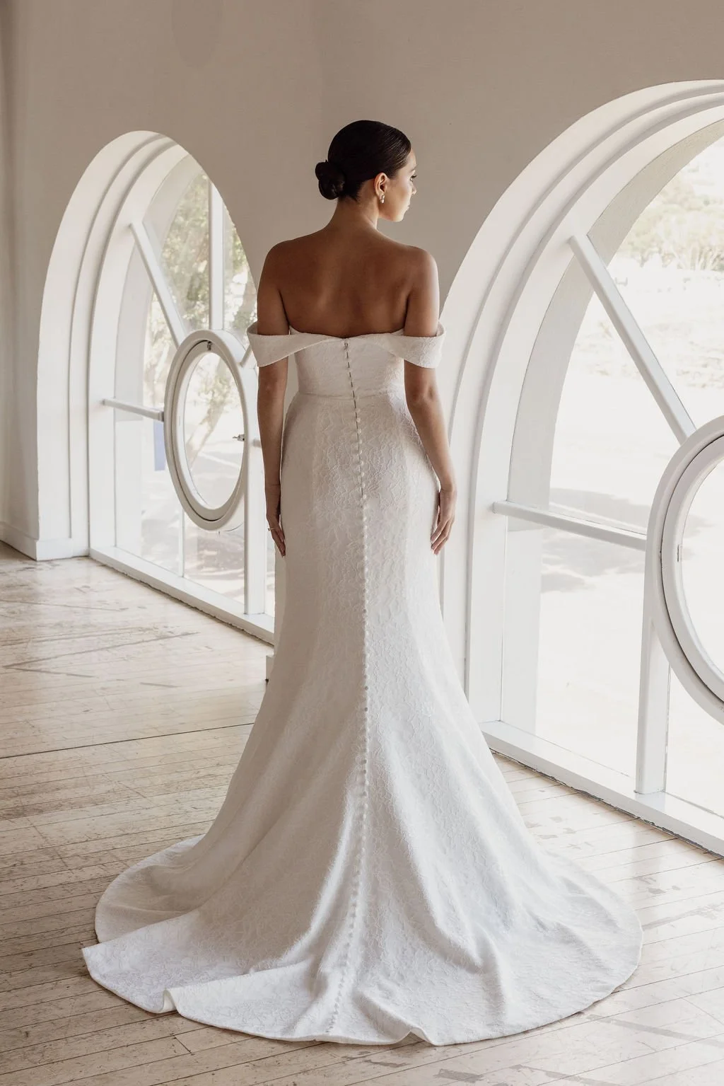 Rosalie by Trish Peng fitted Chantilly lace wedding dress featuring a soft sweetheart off-the-shoulder neckline, draped bodice, ruched skirt and sculpted hourglass silhouette, available at Spellbound Bridal Ireland.
