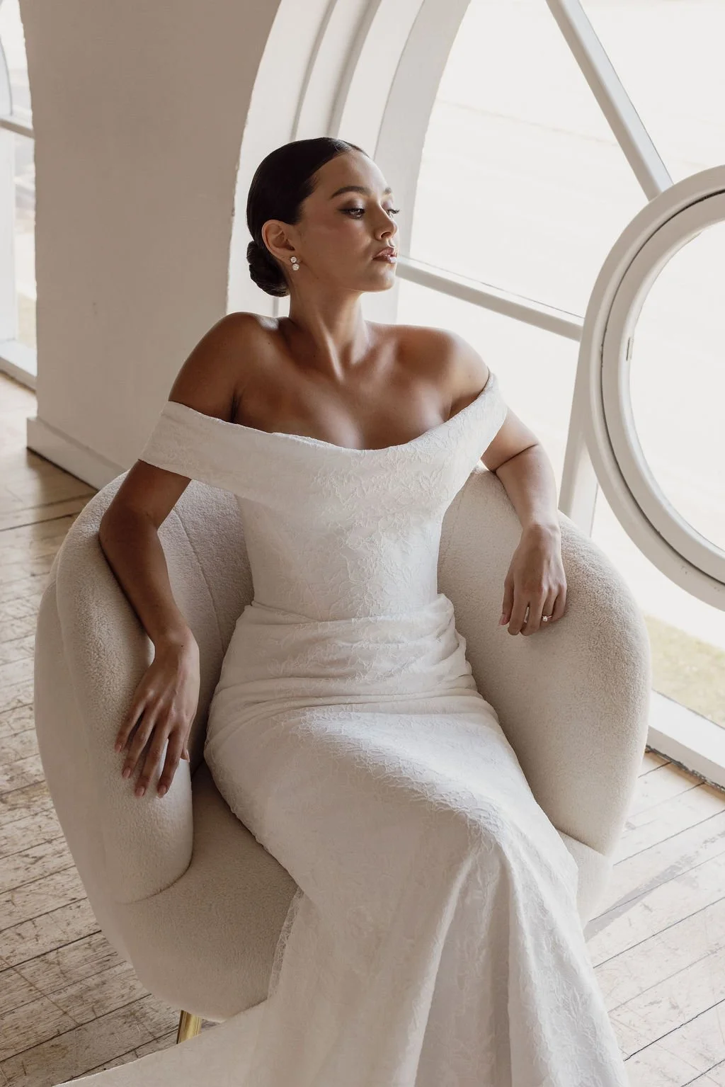 Rosalie by Trish Peng fitted Chantilly lace wedding dress featuring a soft sweetheart off-the-shoulder neckline, draped bodice, ruched skirt and sculpted hourglass silhouette, available at Spellbound Bridal Ireland.
