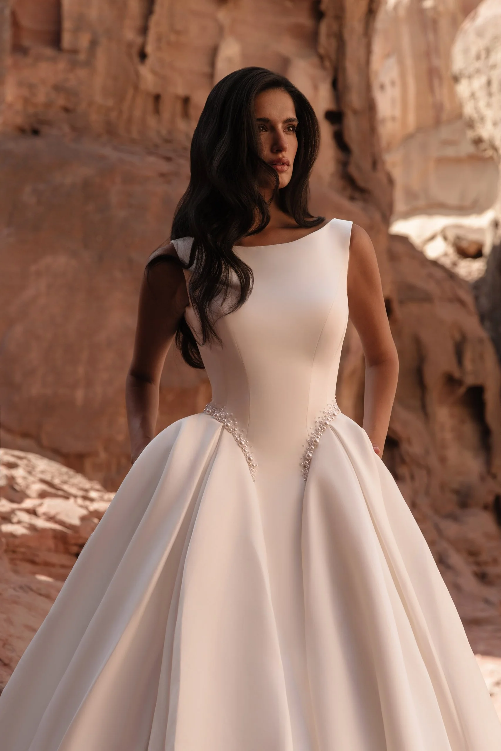 Discover Tori, a minimalist satin princess wedding dress with bateau neckline, structured corset, pearl waist detail and hidden pockets. Available at Spellbound Bridal Ireland.