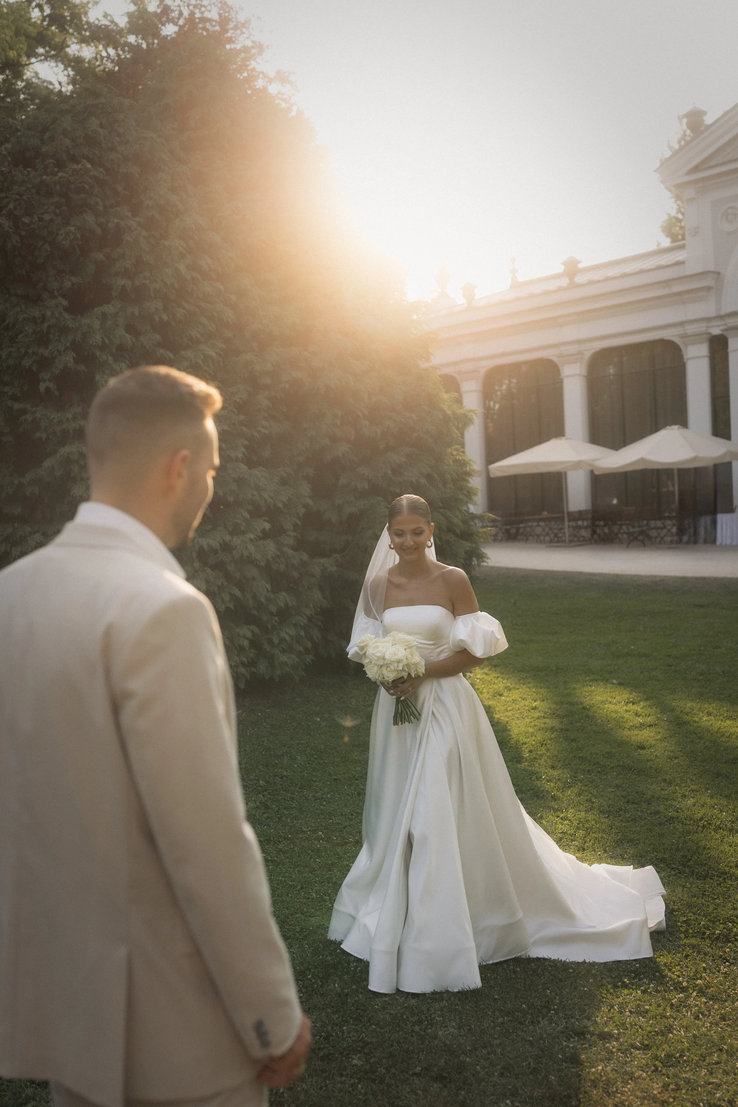 Esküvői pár sétál a Pálma Rendezvényház kertjében - elegáns menyasszonyi ruha és klasszikus esküvői hangulat naplementében