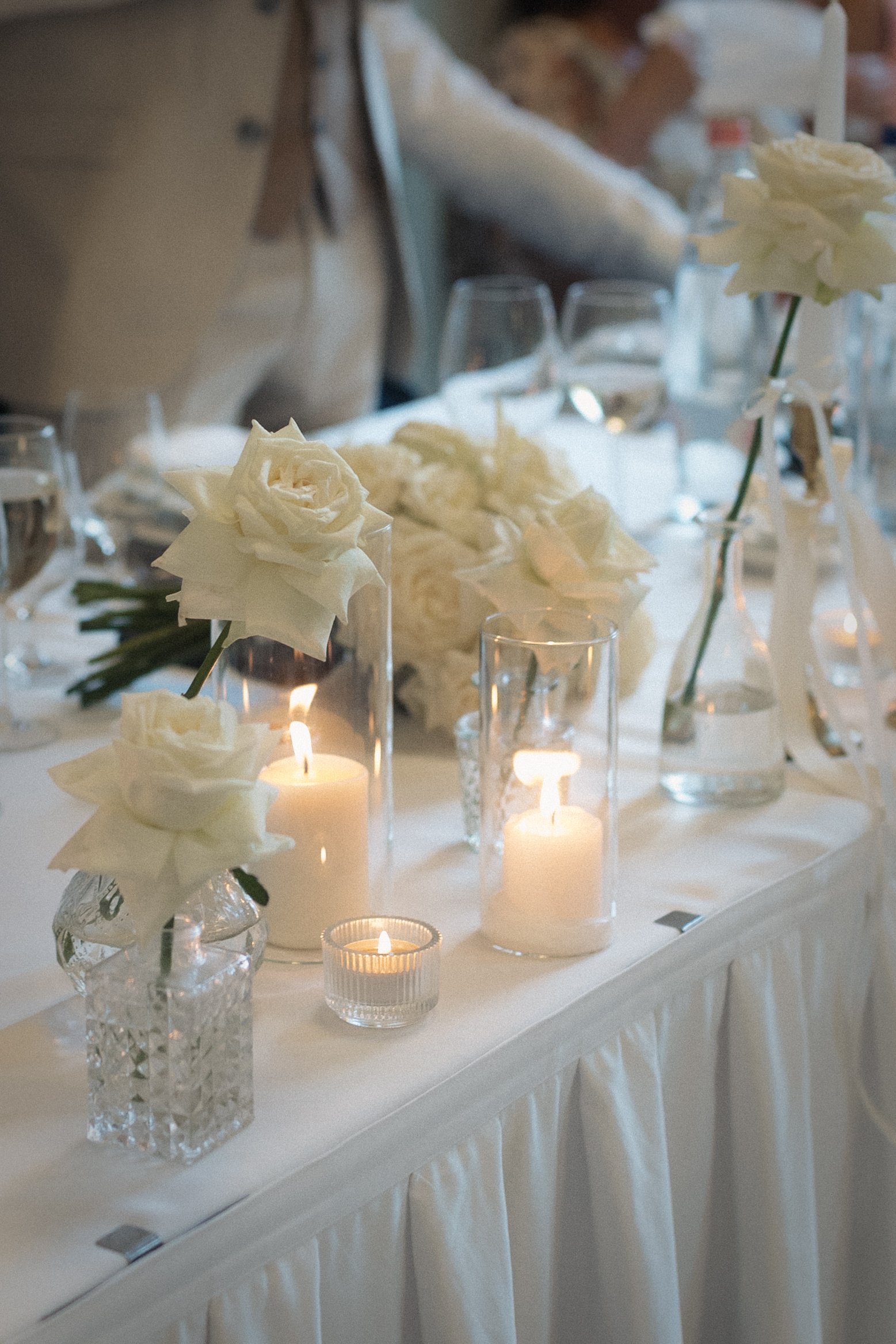 Fehér rózsás főasztal dekoráció gyertyákkal és üveg vázákkal - romantikus esküvői asztaldekor a tatai Pálma Rendezvényházban