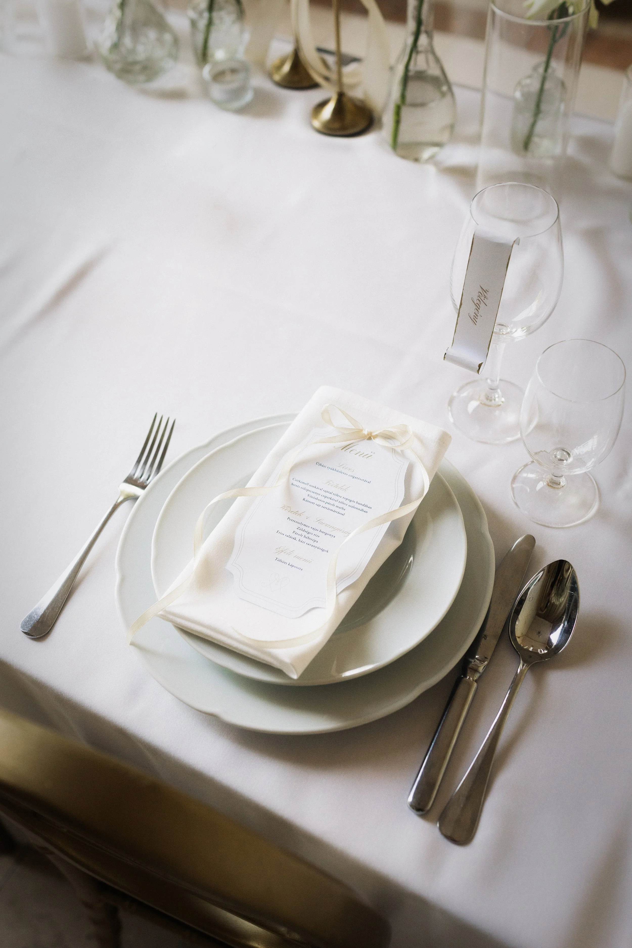 Elegáns esküvői teríték menü kártyával és szalvétadísszel - letisztult fehér asztaldekor a Pálma Rendezvényház esküvőjén
