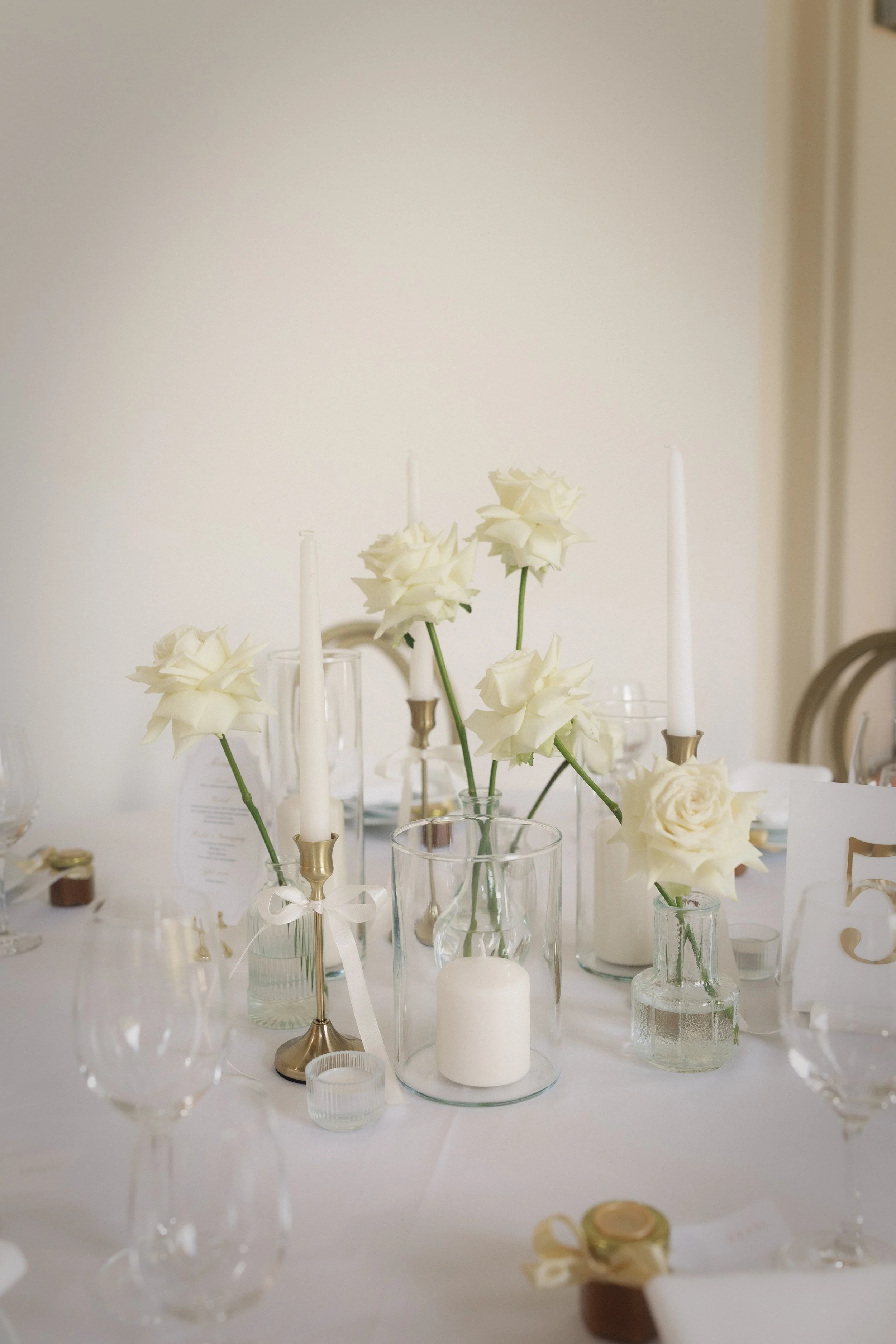 Fehér rózsás asztaldekor üveg vázákkal és gyertyafényes kompozícióval - modern esküvői dekoráció a tatai Pálma Rendezvényházban
