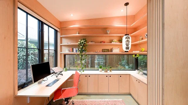 A photo of a small home office with an orange chair and a desk.