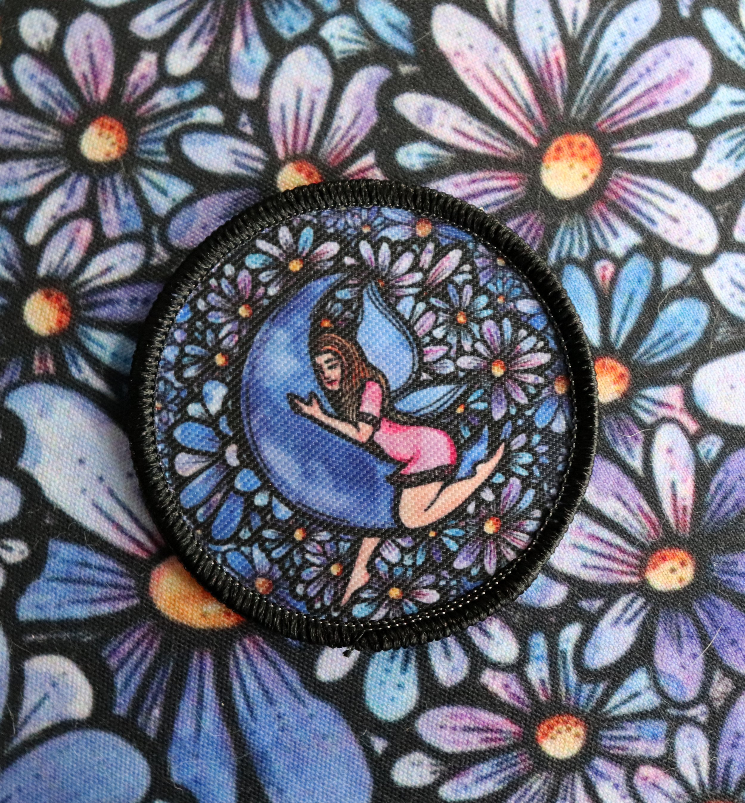 Close-up of floral fabric pattern with multicolored flowers and a black embroidered circular design in the center.