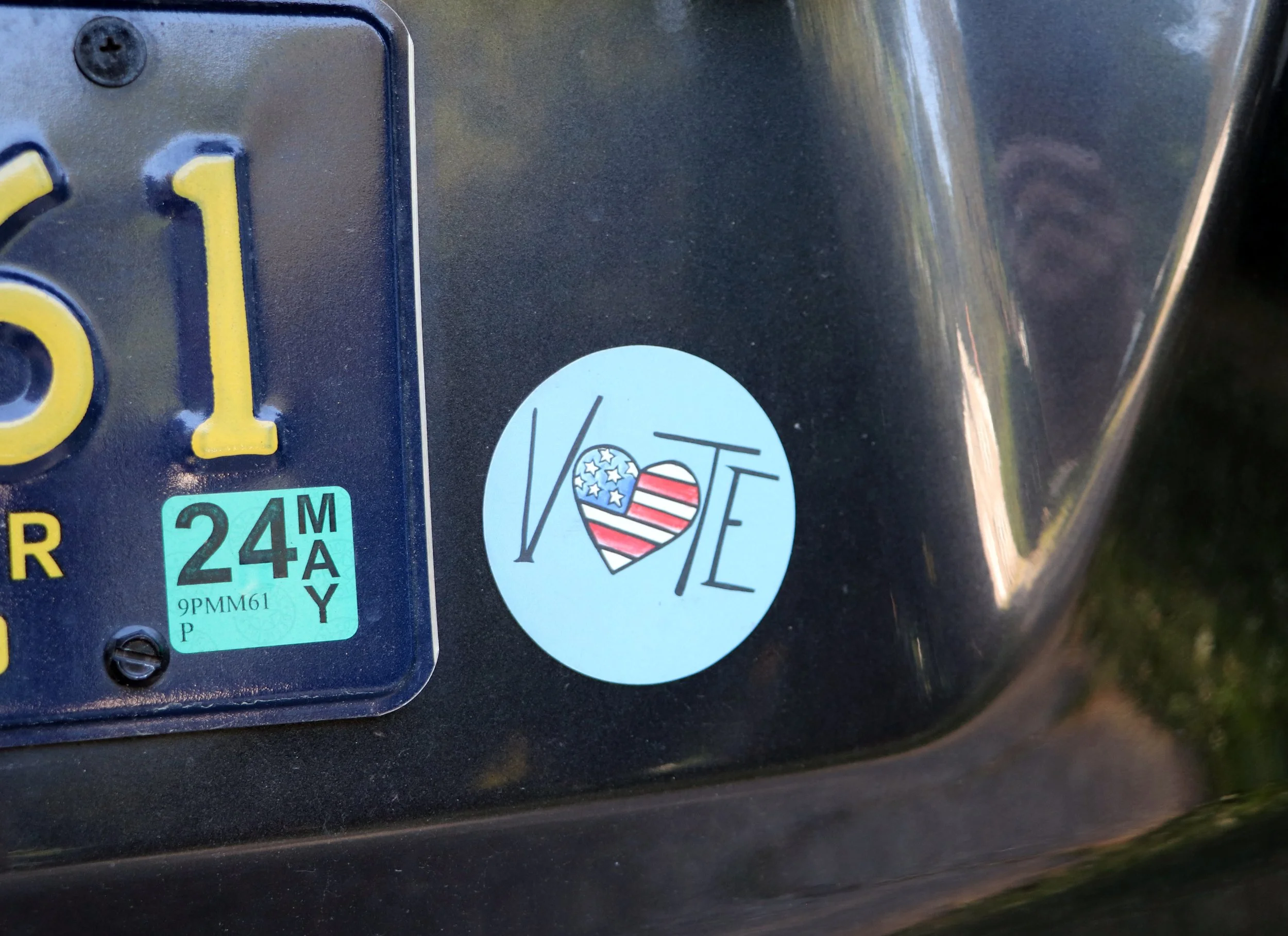 A sticker with the word LOVE and a heart-shaped American flag on a black vehicle
