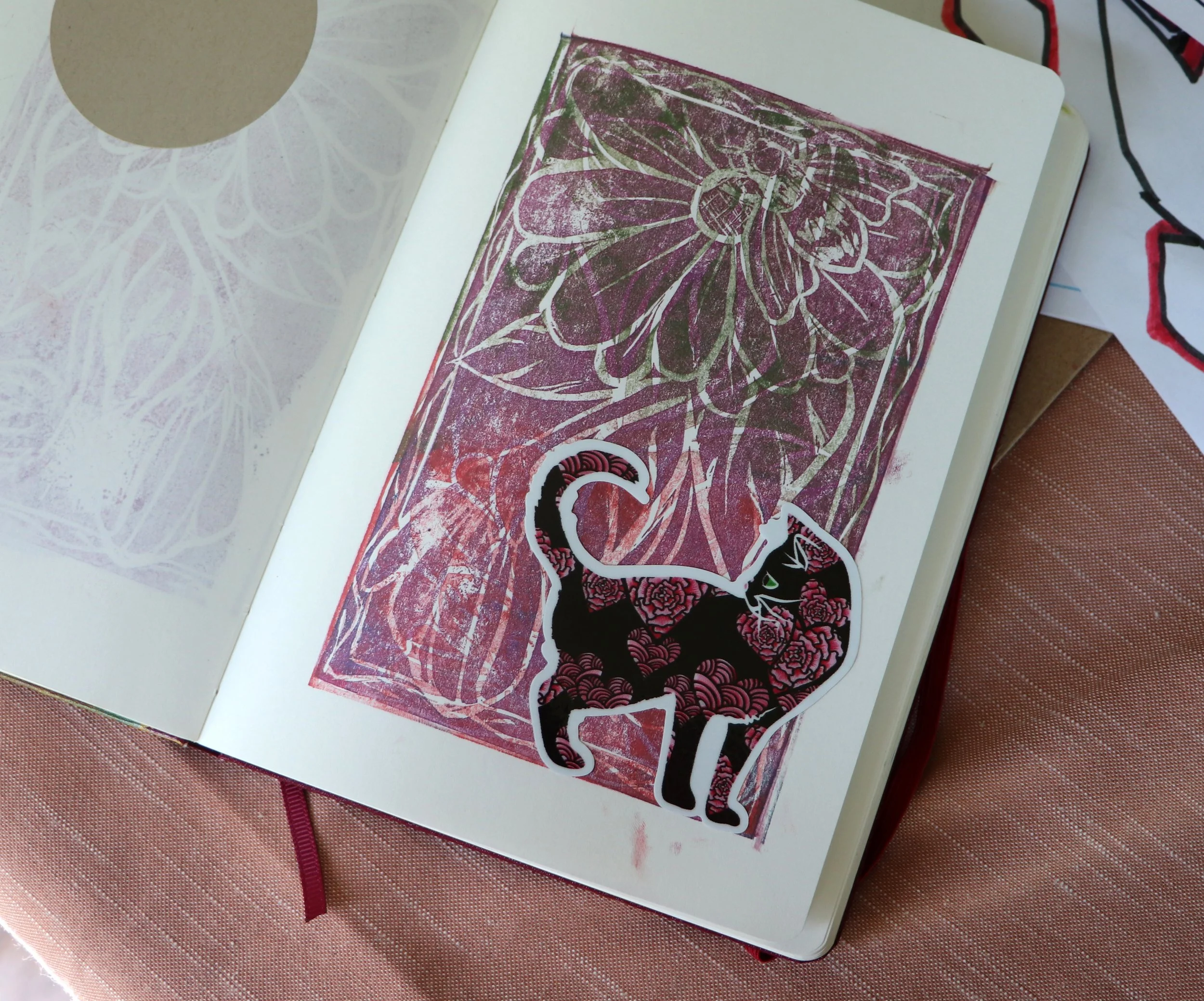 Open notebook with pink and purple floral print background and a black and white dragon-shaped sticker with pink accents.