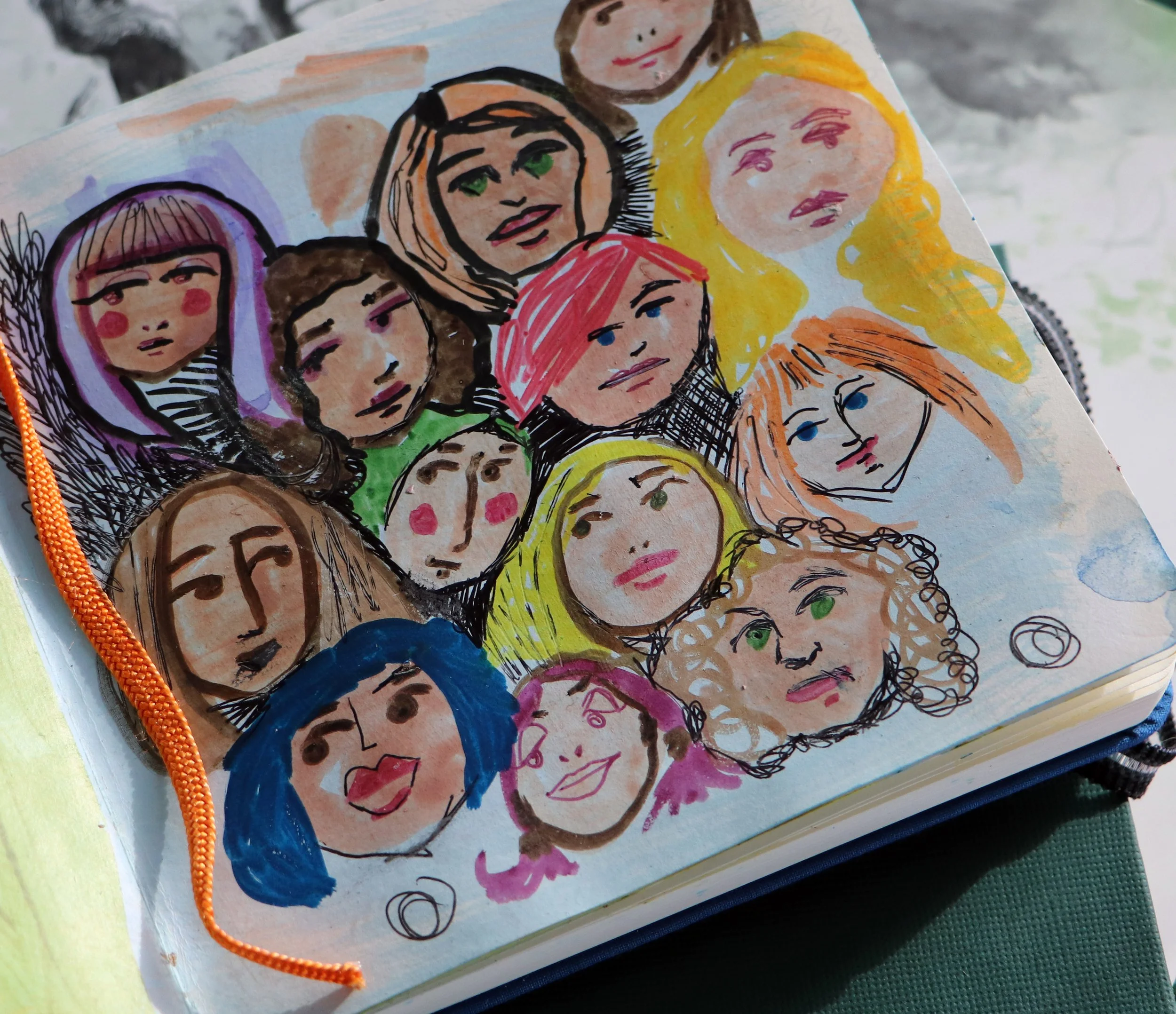 Colorful illustration of multiple women's faces, drawn with markers and watercolors in a sketchbook, featuring various hair colors and styles.