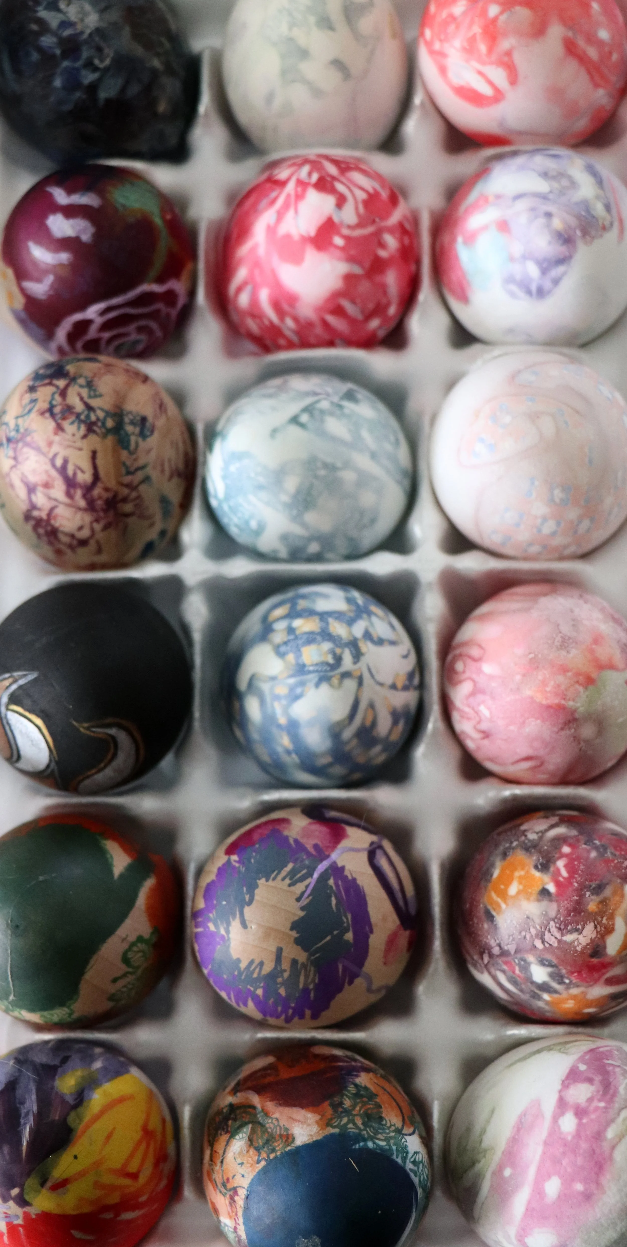 Colorful marble puzzle eggs in a plastic tray.