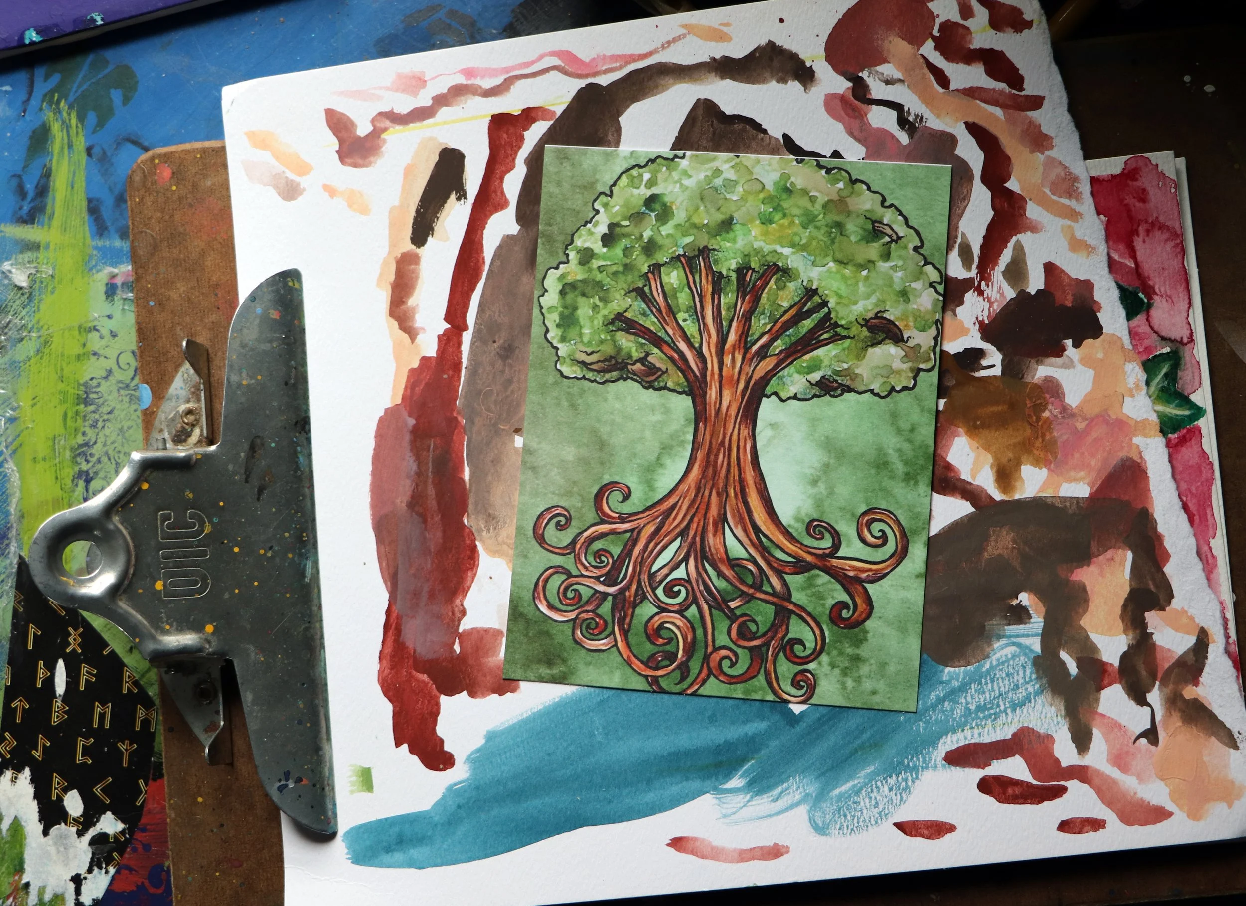 A colorful watercolor painting of a tree with swirling roots on green background, placed on top of an abstract watercolor background with various colors on textured paper.