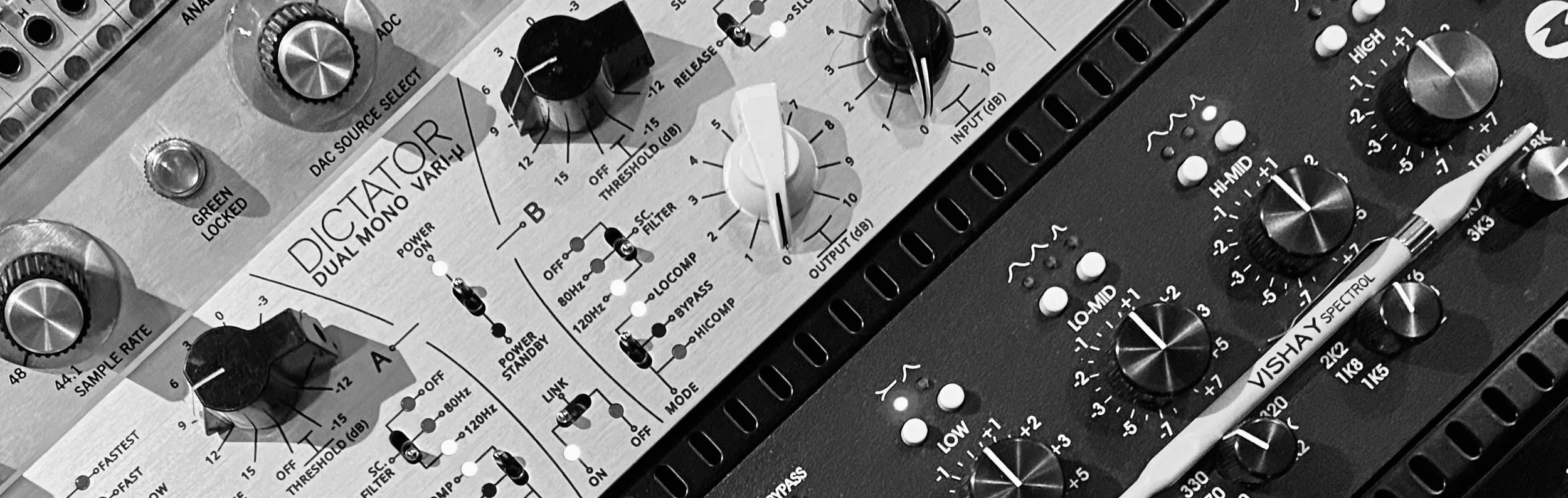 Close-up of audio mixer and equalizer equipment with various knobs and switches in black and white.