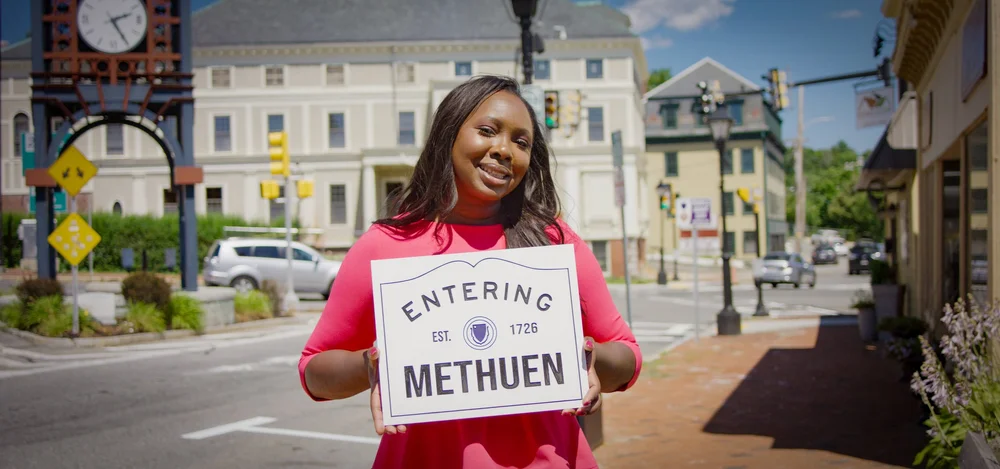 Eunice holding an Entering Methuen sign downtown
