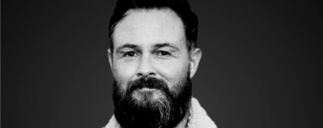Black and white portrait of a man with a beard and short hair, smiling slightly.