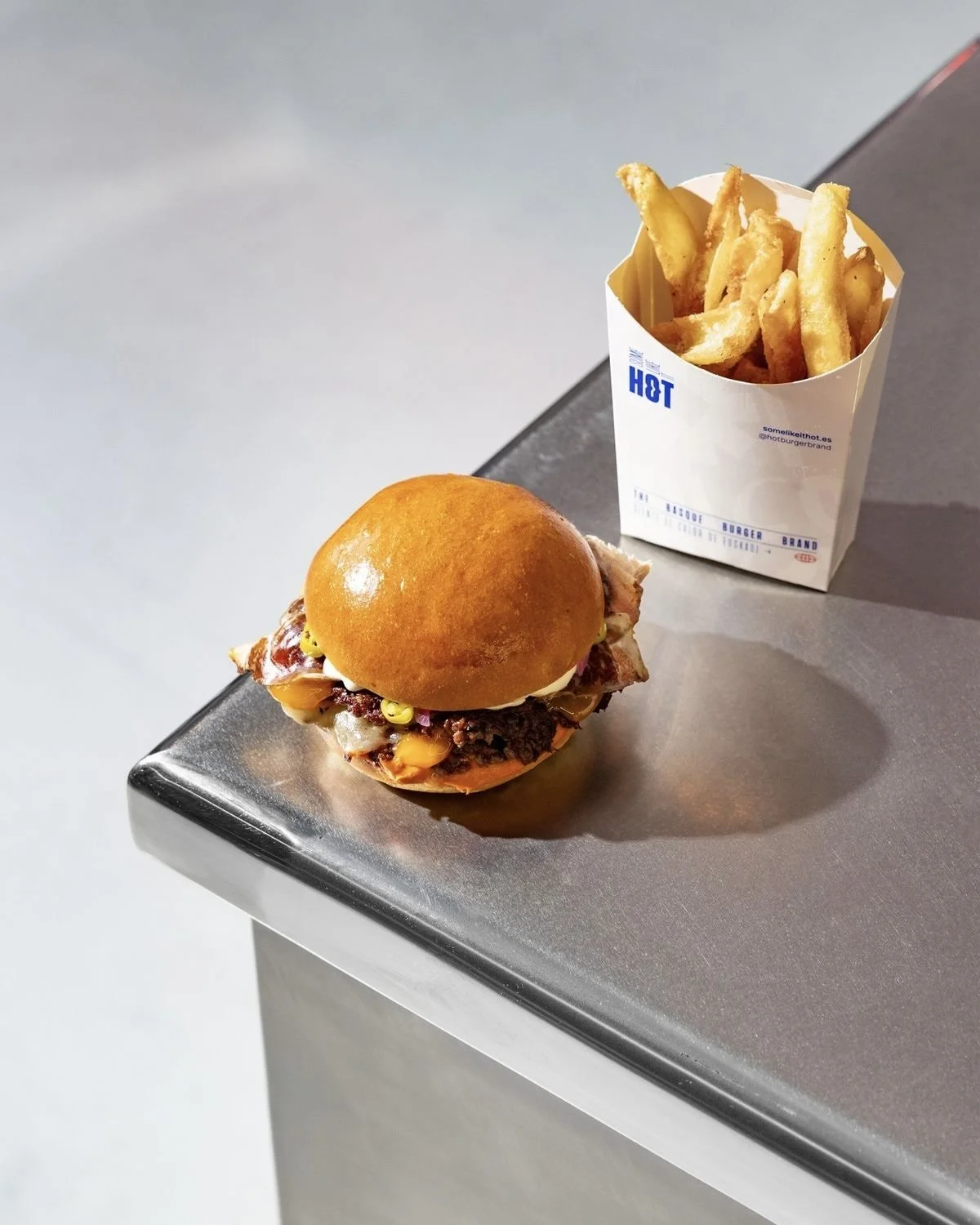 Cheeseburger and fries on a metal counter representing convenience food and modern lifestyle habits.