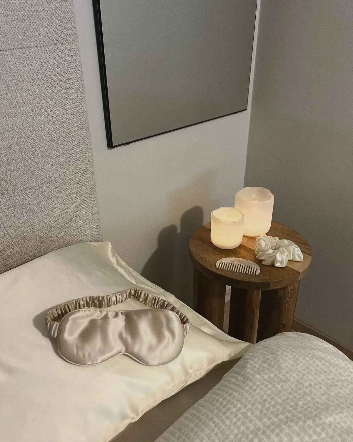 Calming bedtime setup with silk sleep mask, candles, and pillow on bedside table representing a screen-free evening routine for better sleep.