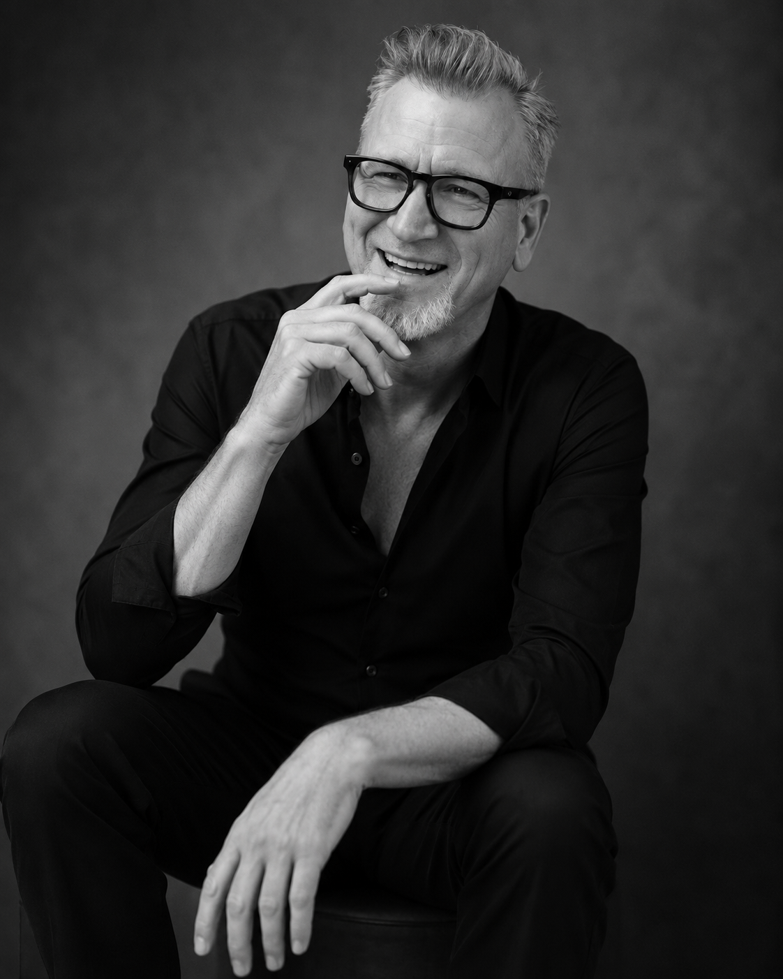Marc laughing on stool All Black.png