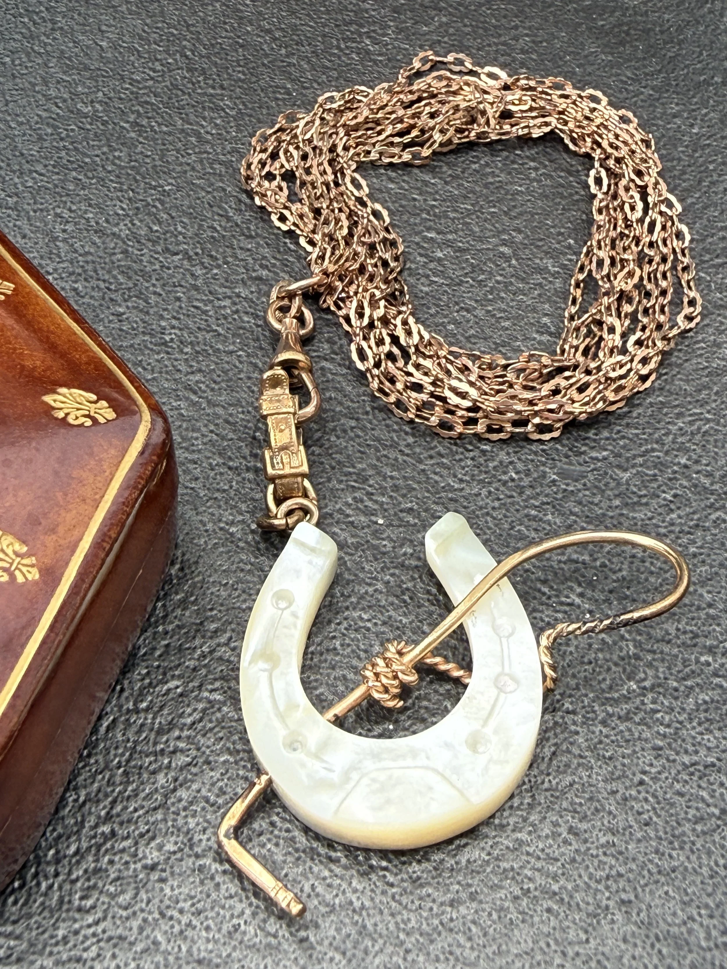 Late 19th century mother-of-pearly horseshoe with riding crop on etched chain