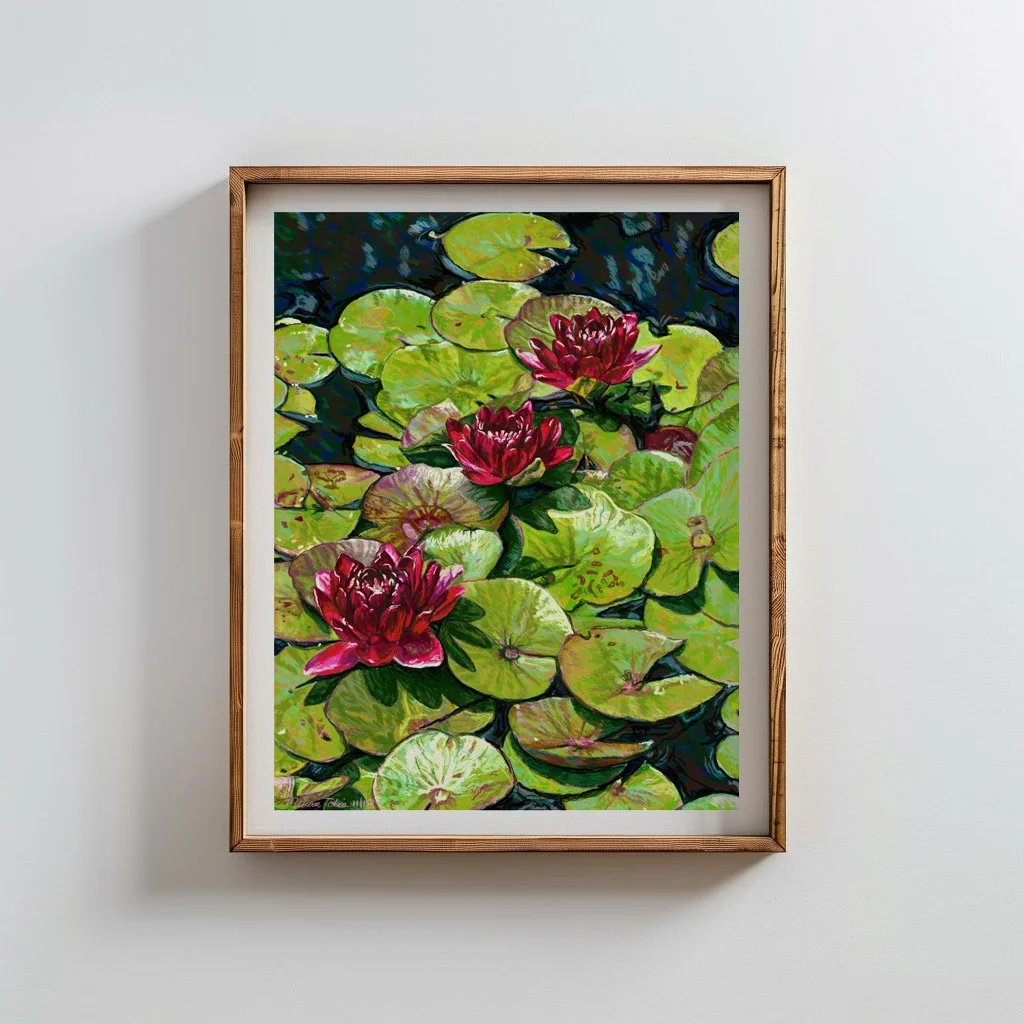 Framed lily pond art in a natural wood frame on a plain white wall