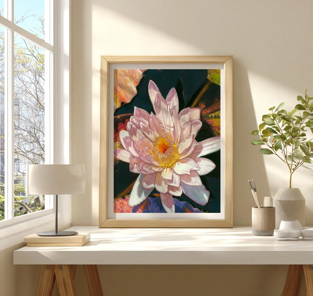 Water lily wall art in a gold frame on a bright windowsill beside a lamp and small plant